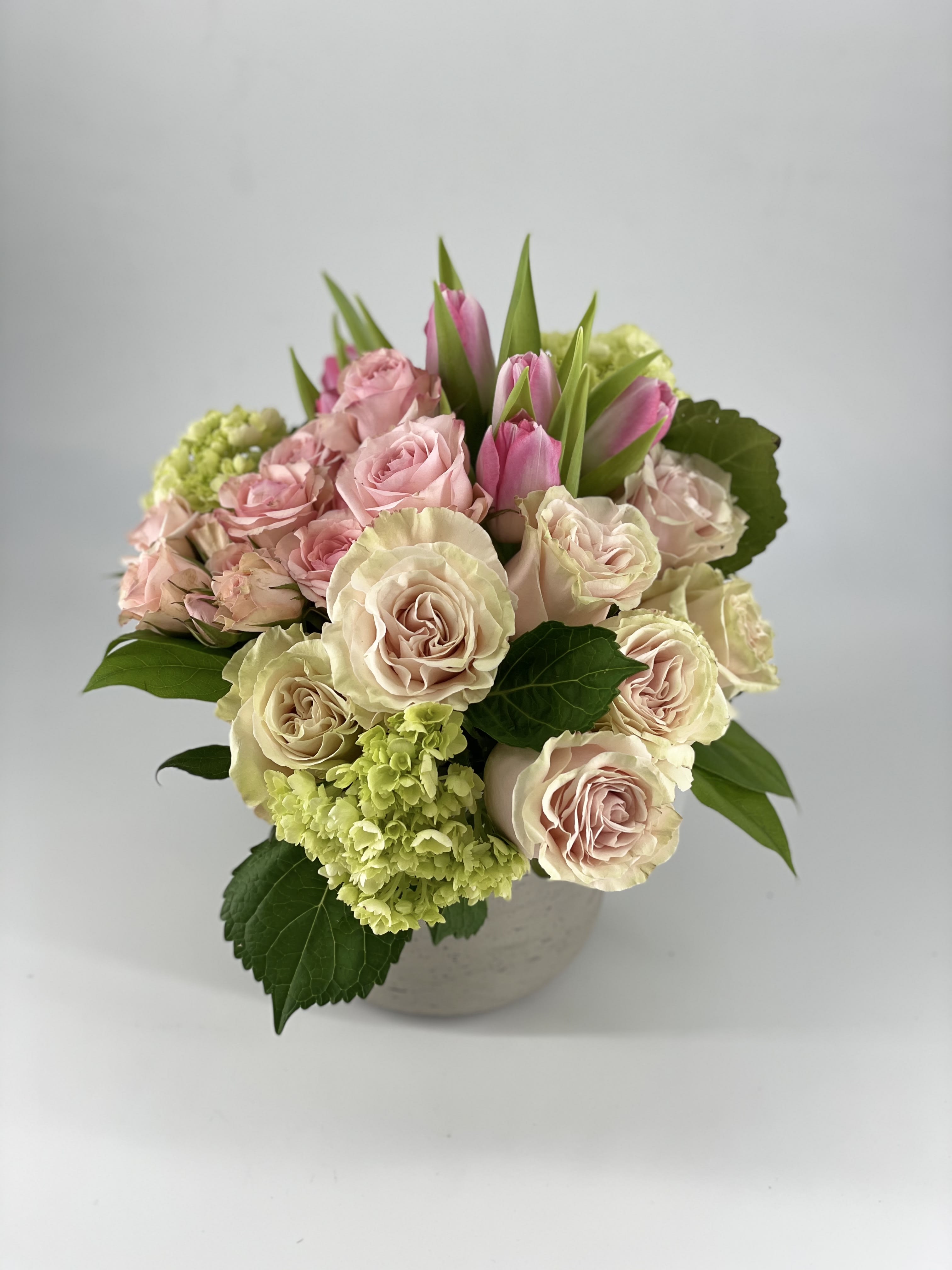 Gathered Rosè - Crisp, refreshing and most importantly Pink. Gathered Rosé is a collection of beautiful pink blooms such as Roses, Tulips and Spray Roses accompanied by green hydrangea in a variety of shades. Arranged in a gathered style in our Concrete Rose Signature Vase, this arrangement is perfect for many occasions.