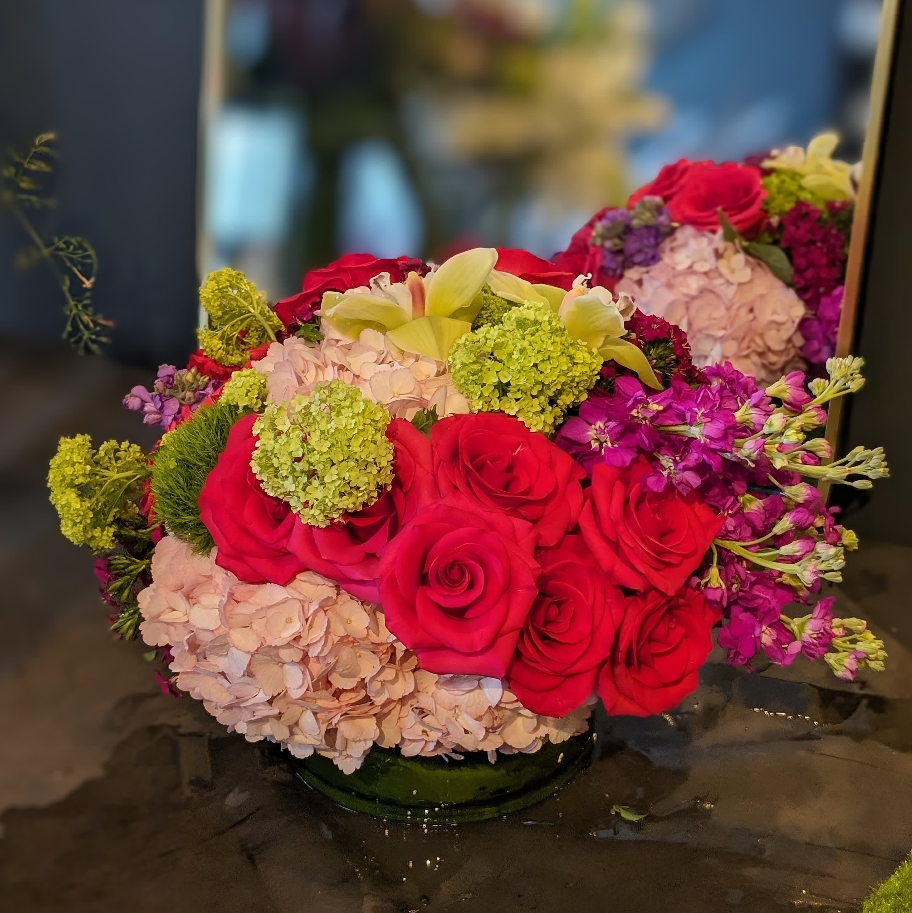Vibrant fuschia, bubblegum and fuschia mix - Gorgeous viburnum roses, orchids and fragrant stock and hydrangea give this springy centerpiece a big look.