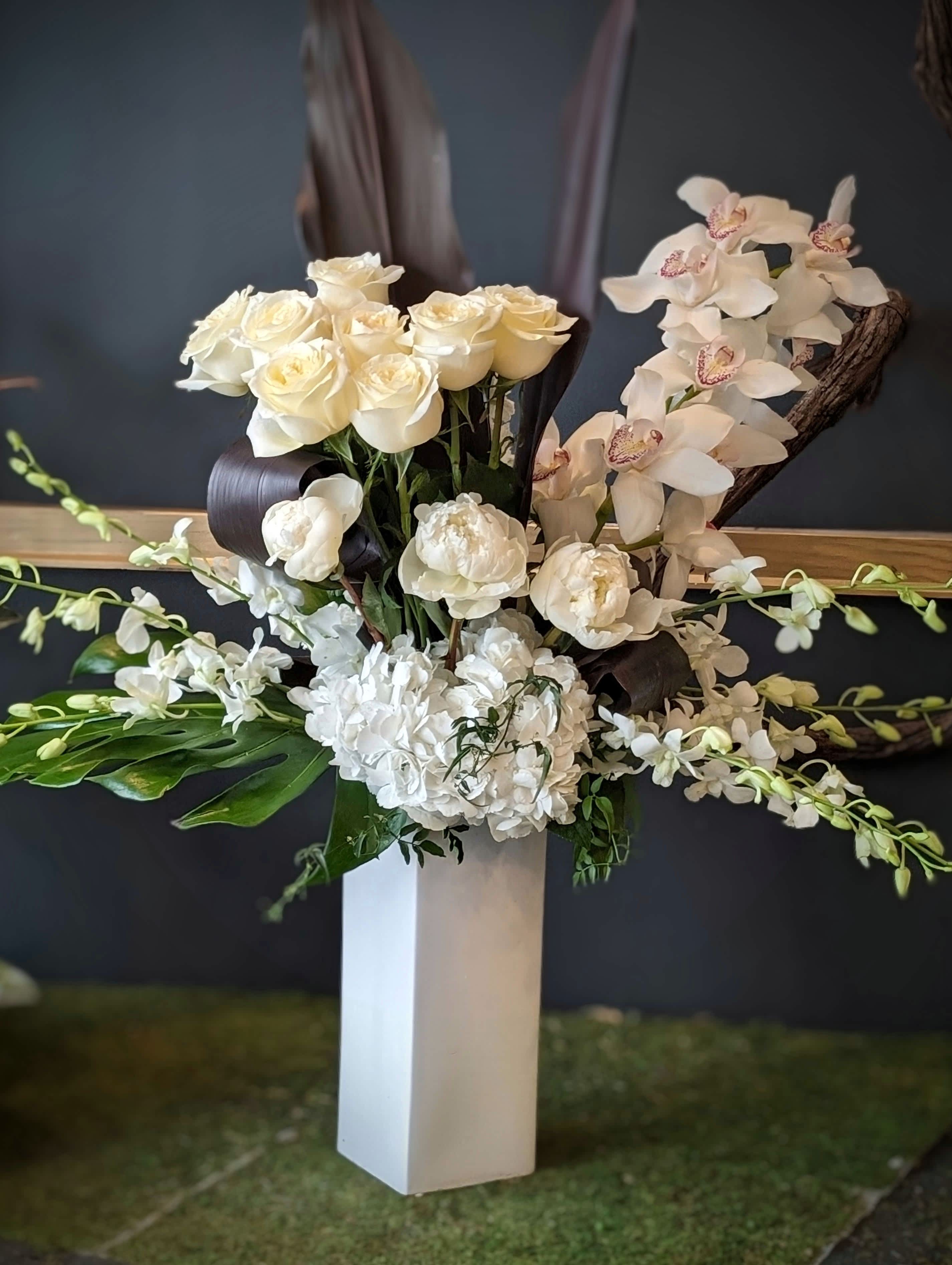 White Focal Stunner - Elegant and tall, white cymbidium orchids roses peonies, hydrangea and curled foliage.