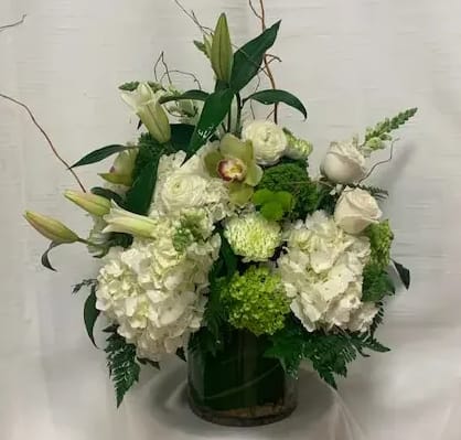 Natural Elegance  - Make a statement with our breathtaking large modern flower arrangement, a stunning display of elegance and natural beauty that features a wondrous array of flowers, including huge white and green hydrangeas, ranunculus, green cymbidium orchids, snapdragons, oriental lilies, roses, and much more!  Expertly crafted by our professional florists, this arrangement is composed of carefully selected blooms that perfectly complement each other in color, form, and texture. The large white and green hydrangeas act as the perfect centerpiece of the arrangement, representing grace, abundance, and prosperity.  The arrangement's unique design is further enhanced by the vibrant green cymbidium orchids, delicately balanced by the soft pink and white hues of the ranunculus, roses, and oriental lilies. The snapdragons add depth, texture, and character, creating a truly mesmerizing effect.  Expertly arranged in a sleek 7x7&quot; cylinder vase and accented with stones and an aspidistra leaf, this modern flower arrangement is the embodiment of luxury, sophistication, and natural beauty. The cylindrical vase adds a touch of modern elegance, beautifully complemented by the natural elegance of the blooms.  This exquisite large modern flower arrangement is perfect for any occasion, from corporate events to grand weddings, or simply as a statement piece in your home. Give the gift of natural elegance and modern sophistication with our stunning arrangement of hydrangeas, ranunculus, cymbidium orchids, snapdragons, oriental lilies, roses, and more.  Experience the captivating beauty of nature with our expertly designed large modern flower arrangement. Revel in the magic of its carefully selected blooms and exquisite design, accentuated by the sleek 7x7&quot; cylinder vase, stones, and an aspidistra leaf. Capture the essence of elegance, tranquility, and natural beauty with this mesmerizing arrangement that is sure to take your breath away. 