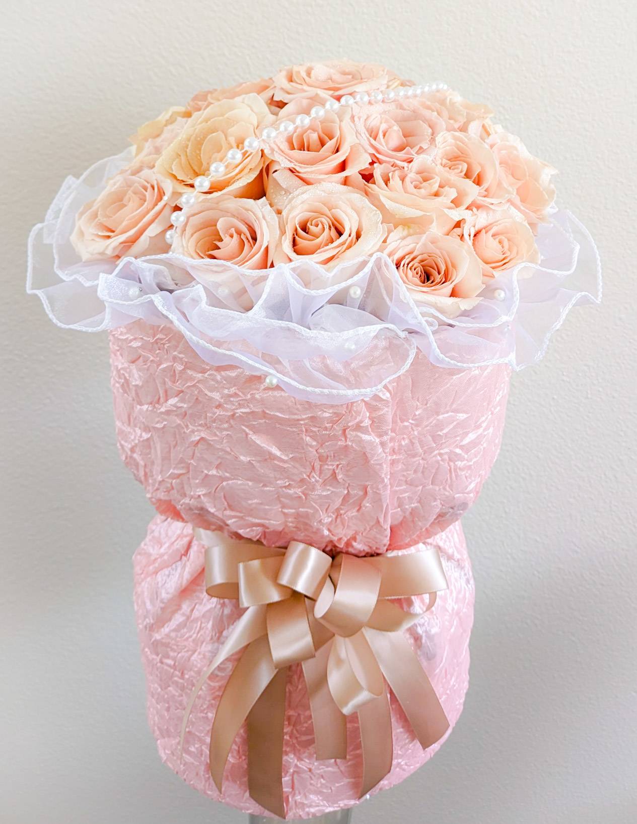 Blush Rose Chanel Style Bouquet Blush Rose Chanel Style Bouquet - 2 dz. Blush roses arranged in a 6"x6" glass cylinder vase and wrapped Chanel Style in blush crinkle taffeta with pearl accents.
