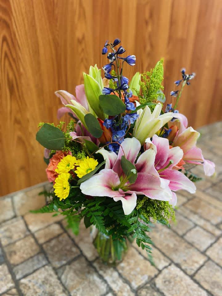 Whimsical Lillies - A whimsical and colorful mix of fresh flowers including lilies, delphinium, chrysanthemum, and assorted greenery. Just to let you know, flowers and vases may vary but we do our best to match the arrangement shown.  