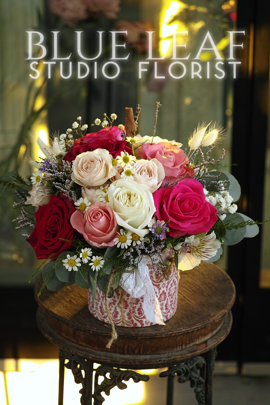 Rustic Love - A gorgeous arrangement of roses in shades of red, pink and white, styled in a low ceramic vase. Includes touches of chamomile, limonium, and babies breath. 