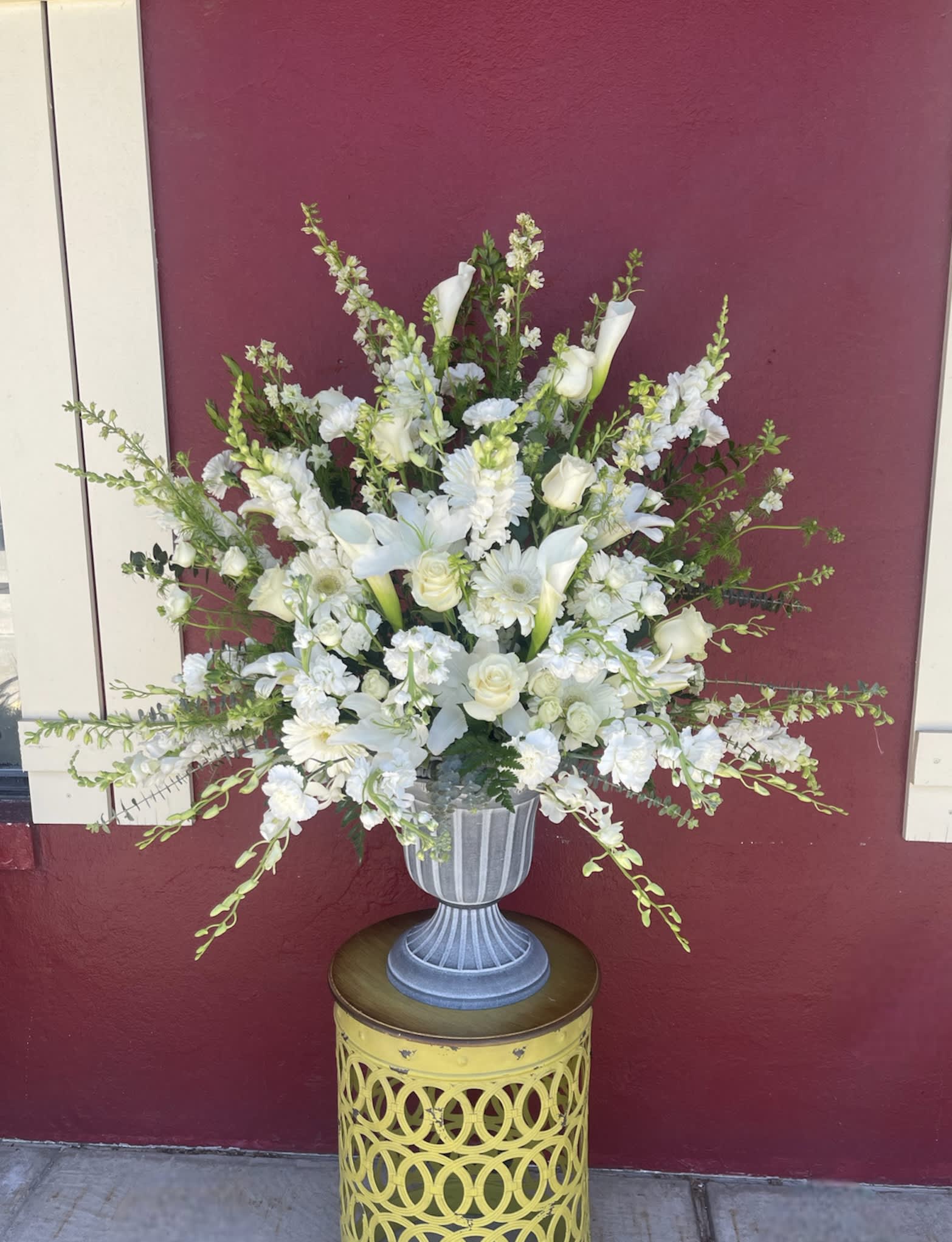 Grand Blanc - Beautiful seasonal flowers congregate in a large urn. This arrangement is appropriate for any special occasion. It's grand size is perfect for grand entrance, buffet, altar or podium placement. Other colors are available, specify in special instructions or call the shop. 
