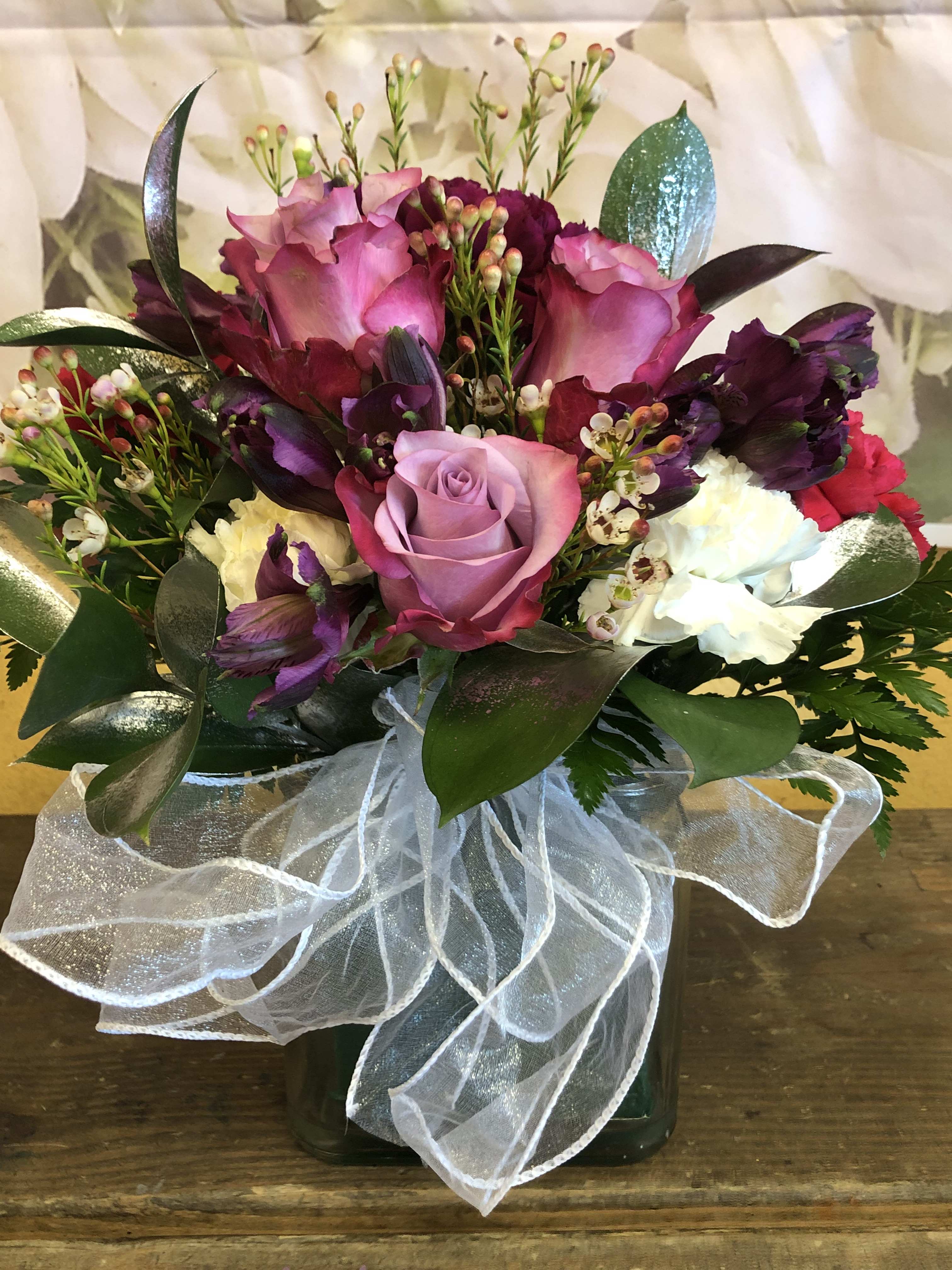 PURPLE AND WHITE (DESIGNER CHOICE ) CUBE PURPLE AND WHITE (DESIGNER CHOICE ) CUBE - Purple and white flowers to include roses, carnation and liles in a cube with filler. NOTE ARRANGEMENT IS DESIGNER CHOICE.