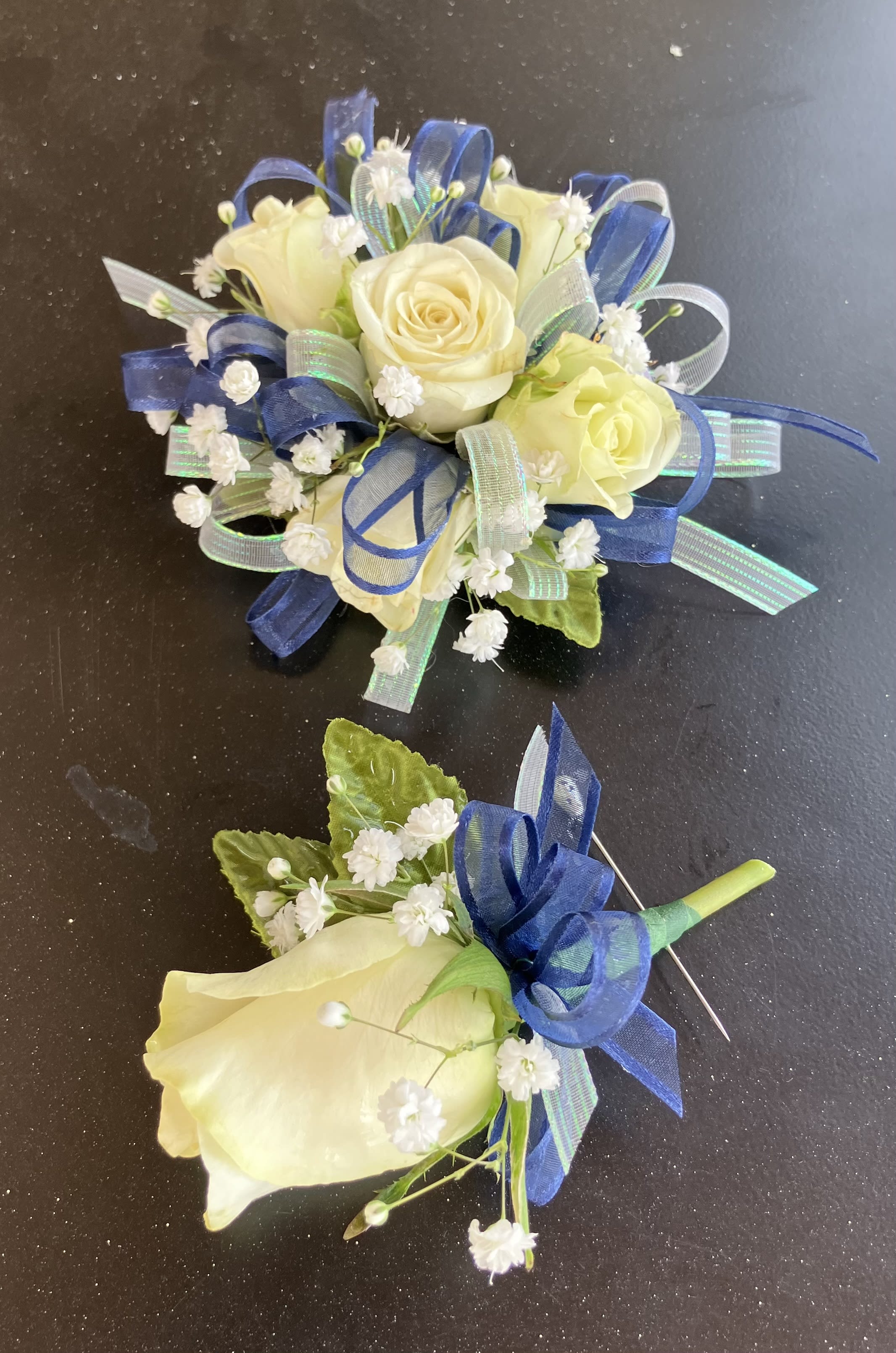White Rose Corsage and Boutonniere Set with Blue - This beautiful white rose corsage and boutonniere set with blue can be customized for your perfect prom night! These can be ordered separately, $29.99 for the corsage and $9.99 for the boutonniere.