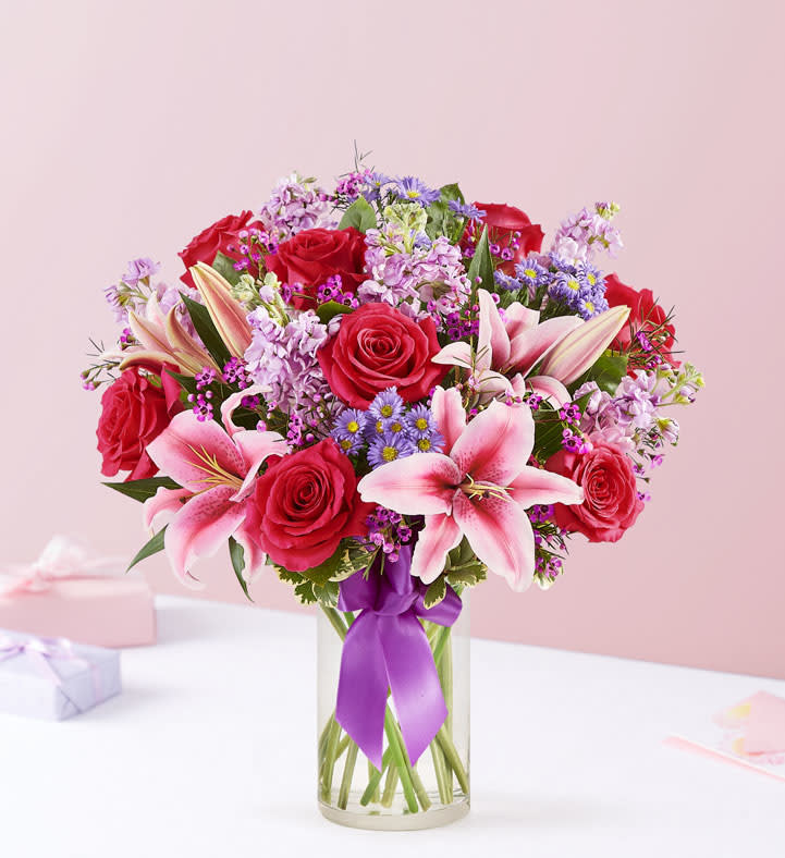 Straight From The Heart - Hot pink roses, pink lilies, lavender stock, wax flower, purple monte casino, arranged in clear glass vase. 
