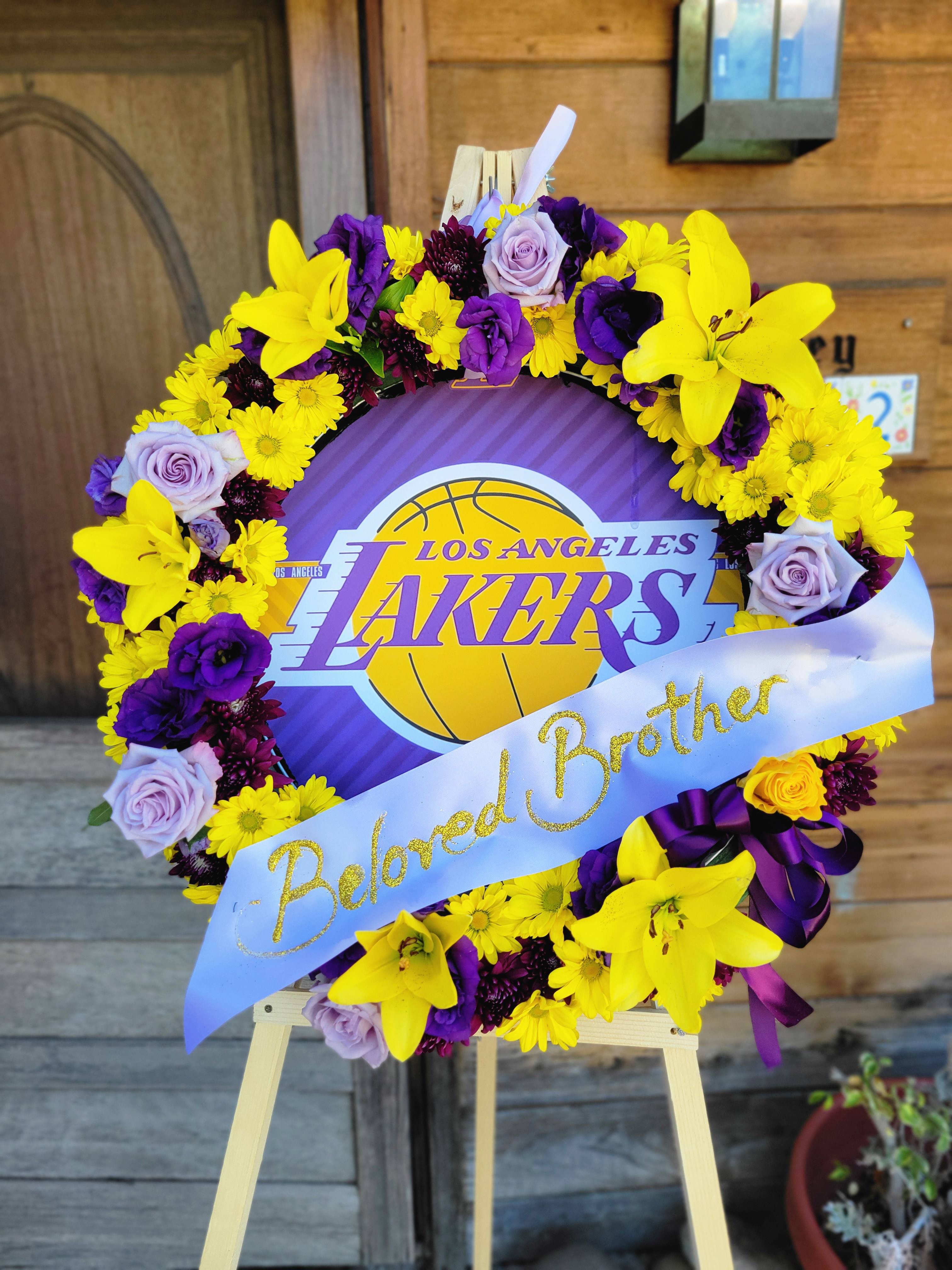 Lakers Standing Funeral Wreath - The Lakers Funeral wreath has been a popular choice for funeral services to commemorate a loved one's cherished sports team. This wreath features a multi floral design in the required colors of Yellow and Purple, lillies, Roses, Lisianthus, and Daisy May appear in this design. This Wreath comes readily equipped with Lakers Imagery and stand. Ready to arrive to your funeral service.  Our standard size is 21&quot; deluxe 24&quot; Premium 30&quot;  We recommend placing funeral service orders 2 day's prior to the service date. 