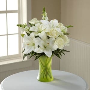 The FTD® Eternal Friendship™ Bouquet -  An exuberance of bright and beautiful white blossoms provides an exquisite way to deliver your expressions of sympathy and comfort. This life affirming tribute combines white roses, snapdragons and Asiatic lilies accented by lush greens arranged in a matte, green glass gathering vase. An excellent choice for a wake, funeral service or for sending your condolences to the home of grieving family or friends. 