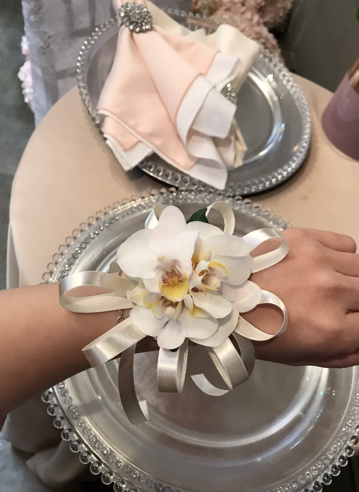 White orchid corsage  - A classic white phalaeposis orchids corsage compliments any outfit. Perfect for prom, formal, and weddings. Substitution Policy In some instances, our photo may