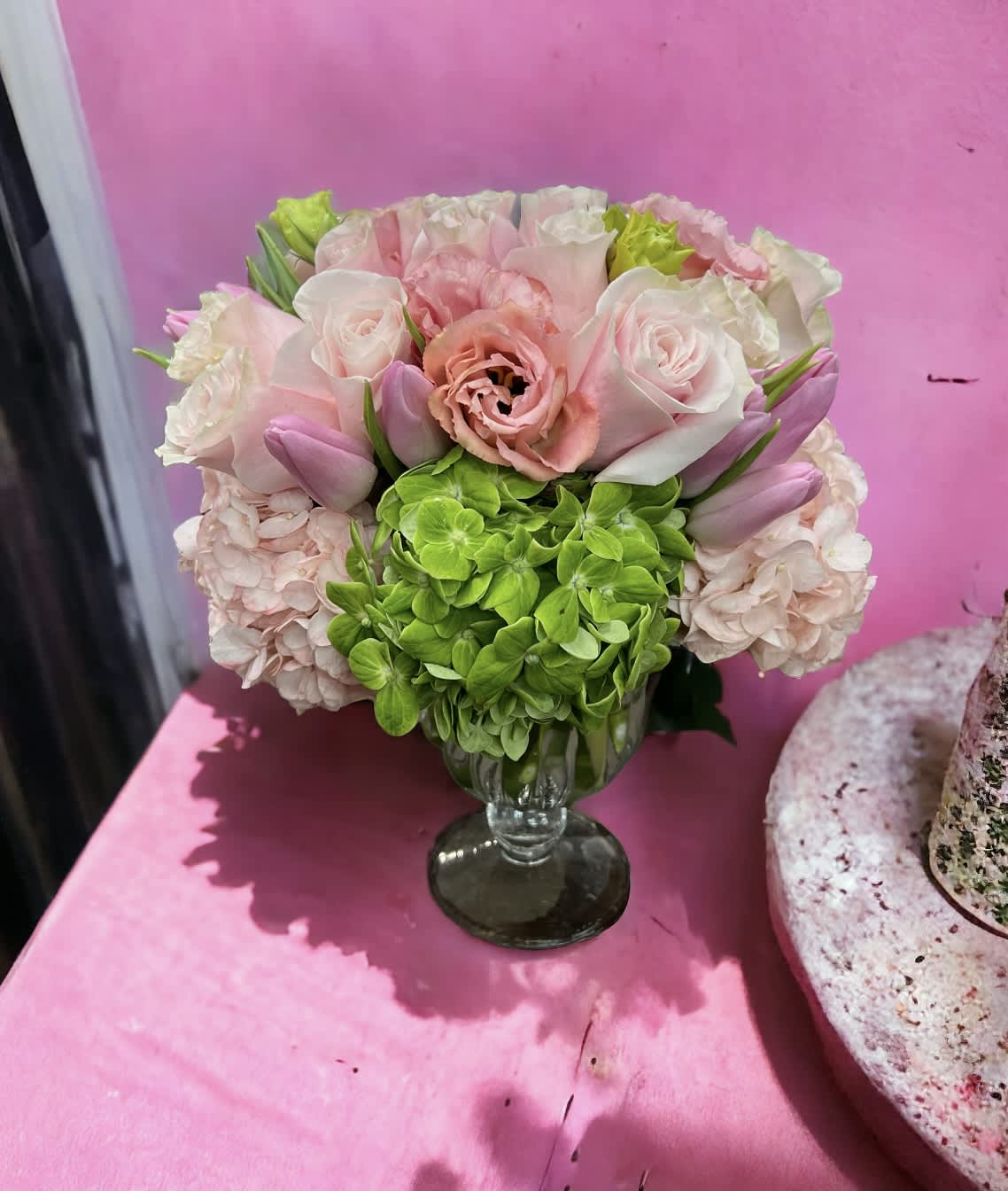 Baby girl! - Lush pastel tones can be seen in delicate Pink, Green hydrangeas, pink roses, pink tulips, pink Lisianthus  Resting inside a beautiful 6” by 5” glass pedestal, overall this arrangement stands approximately  10“tall.