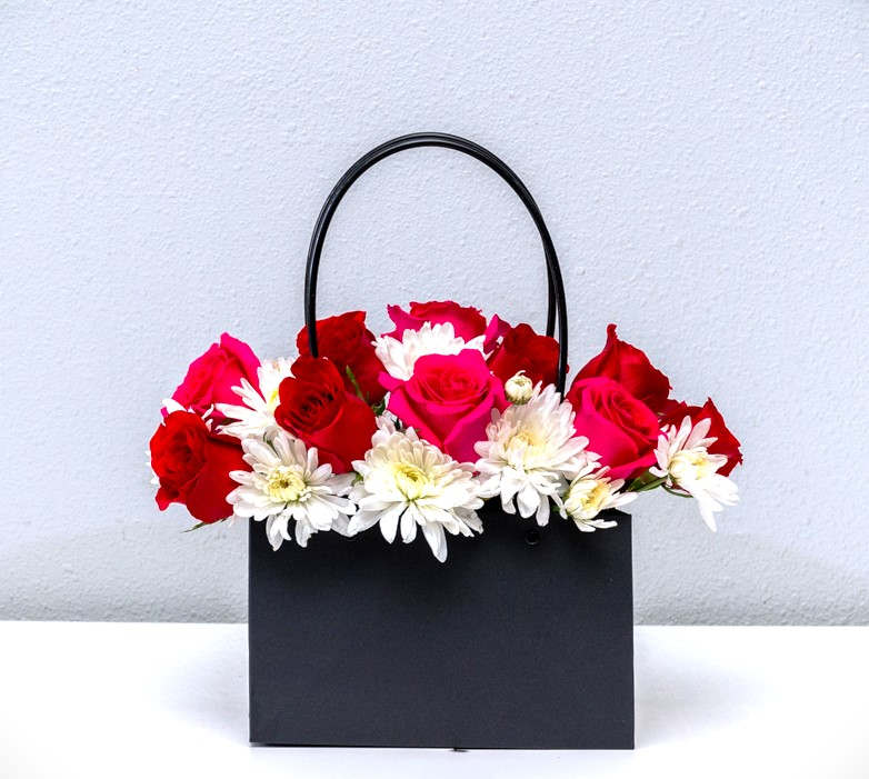 She's on the go... - Lovely arrangement for a fancy gal that's on the go. Purse style container , with exploding roses and other flowers from within. (Standard 8-10 roses with) All held together with a foam block inside.