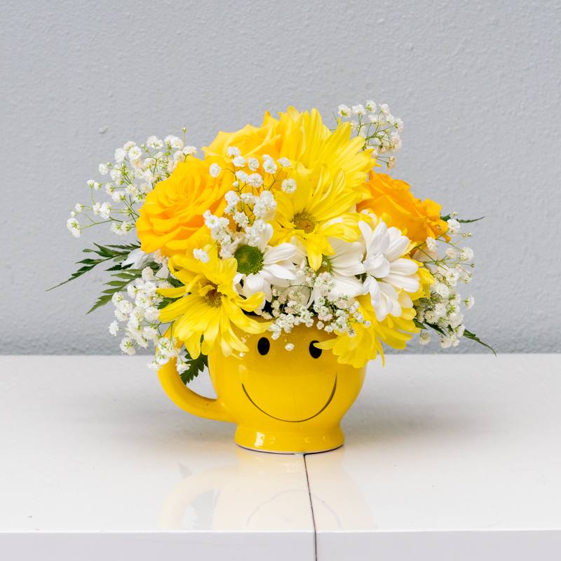 Smile the day away. - Bright yellow roses, daisy's and fillers in a ceramic smiley mug