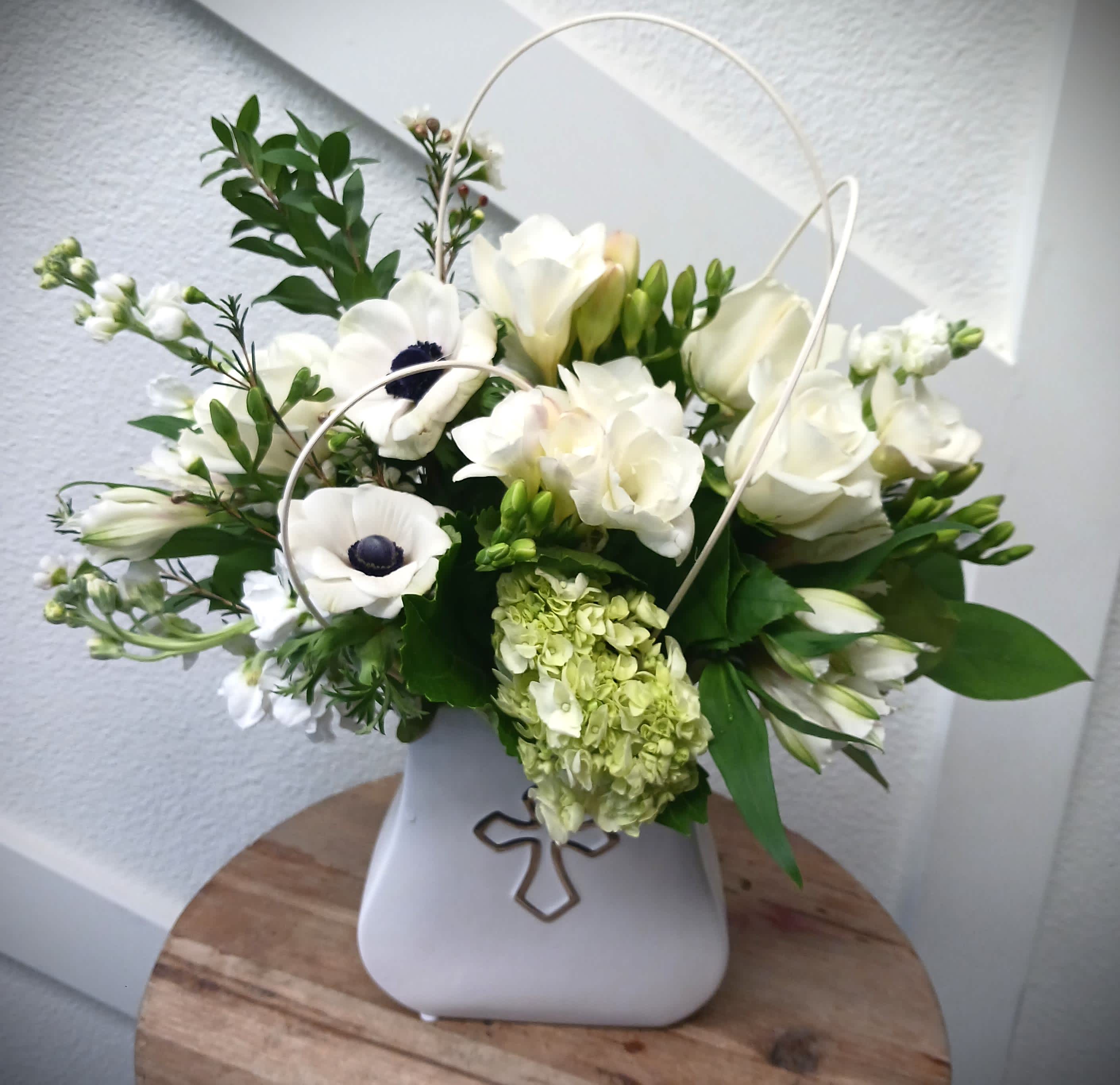 Graceful Memories - For the times when words cannot express how you feel, let the flowers speak for you. This premium all white spring mix features seasonal flowers such as freesia &amp; anemones designed in a keepsake ceramic cross vase. Our designers will always use the freshest of items when creating this seasonal arrangement. 