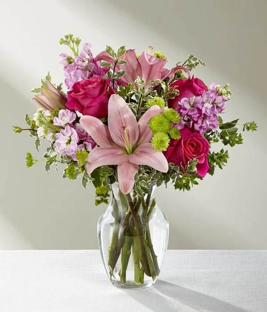 The Pink Posh Bouquet - The Pink Posh Bouquet is chic and pink to help you celebrate life's most treasured moments in style! Hot pink roses are bright and beautiful arranged amongst pink Asiatic Lilies, pink gilly flower, green button poms, bupleurum and lush greens to create that perfect gift of flowers. Presented in a clear glass vase, this blushing fresh flower arrangement is ready to send your sweetest wishes in honor of a birthday, an anniversary, or as a way to express your thanks and gratitude. VASE WILL VARY