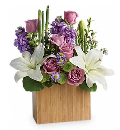 Kissed With Bliss Bouquet - An elegant way to show you care, this bit of bliss blends luxurious lavender roses, lavender stock, wondrous white lilies, green button mums and purple monte casino asters into a stunning floral sculpture.  Accented with exotic greens and presented in a contemporary, natural bamboo vase, this bouquet will bring beautiful serenity to any space.  . Delivered in a large Bamboo Rectangular vase.