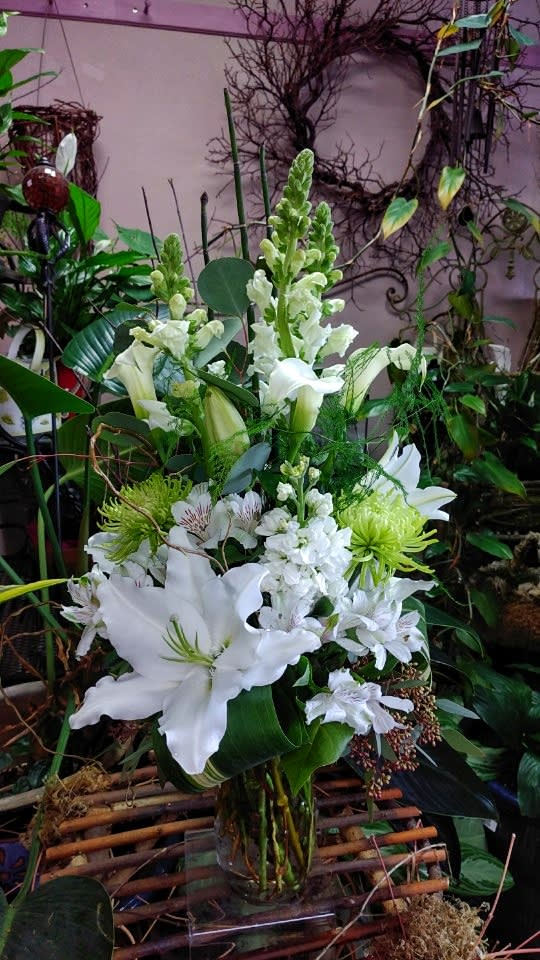 Pure Embrace Pure Embrace - This beautiful pure white arrangement is designed using lilies, stock, snapdragons, calla lilies, alstroemerias, spider mums, eucalyptus, aspidistra, and filler greens. Dimension: 25"x14"