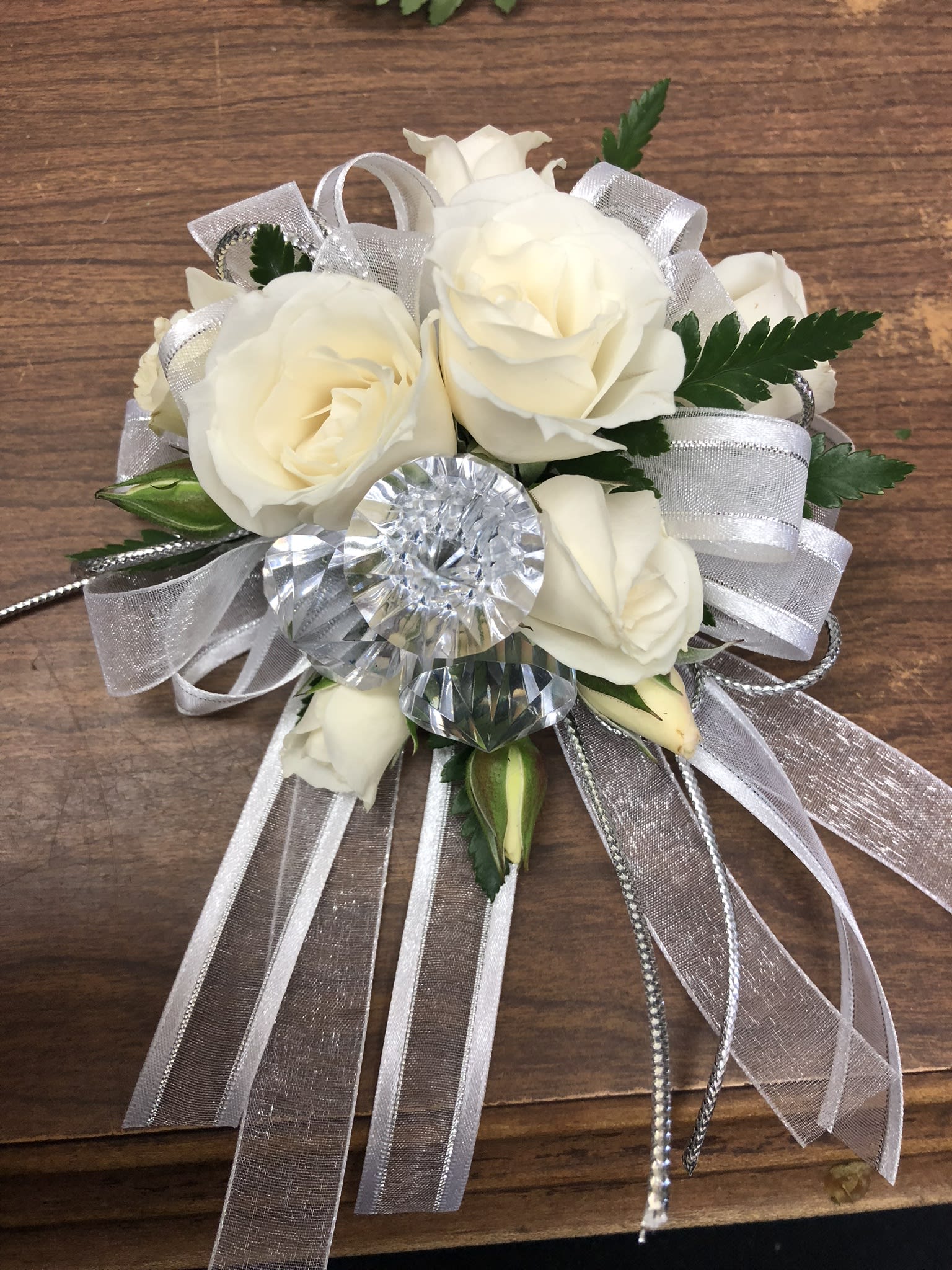 White Corsage - An all white corsage with rhinestone accents of the designers choice. Please include in the special instruction if you'd like to add an accent color rather than rhinestones DELUXE HAS RHINESTONE BRACELET