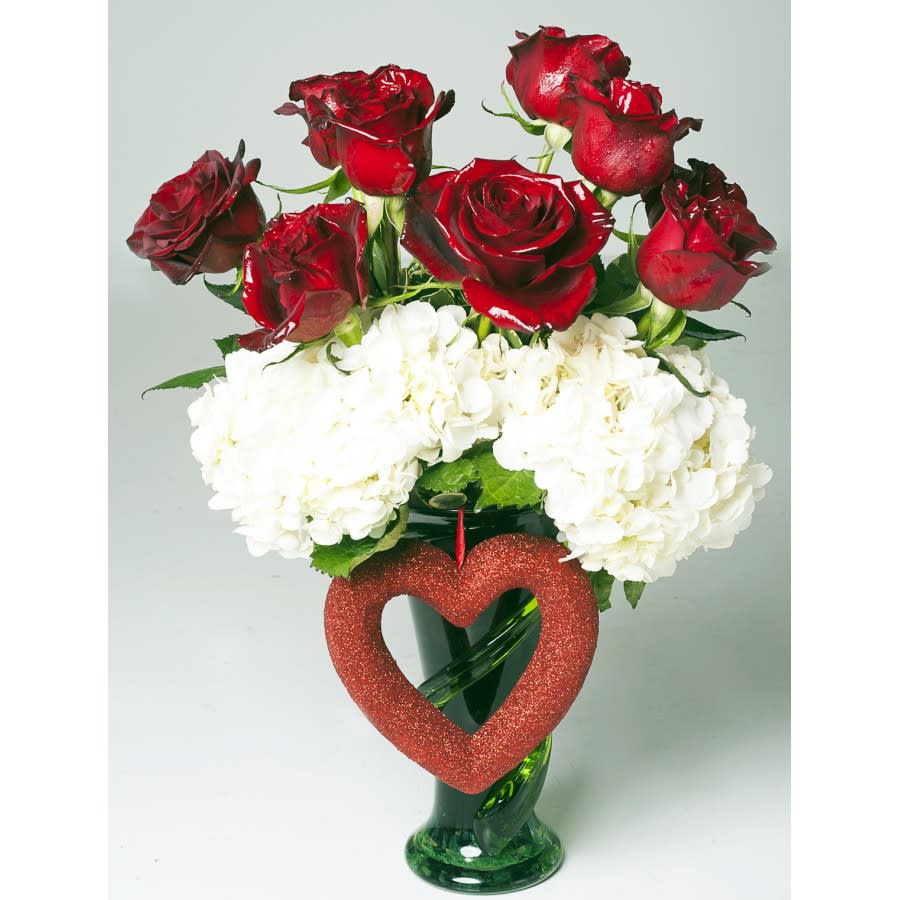 Red, White, and Love Red, White, and Love - "Our exclusive ""Red, White, and Love"" arrangement comes with a different approach to red roses. Each rose is individually sprayed with a glossy finish, allowing them to glow against any light. Included are 8 red roses, white hydrangeas, and a glass green vase. A glitter heart hangs off the vase to complement the arrangement. "