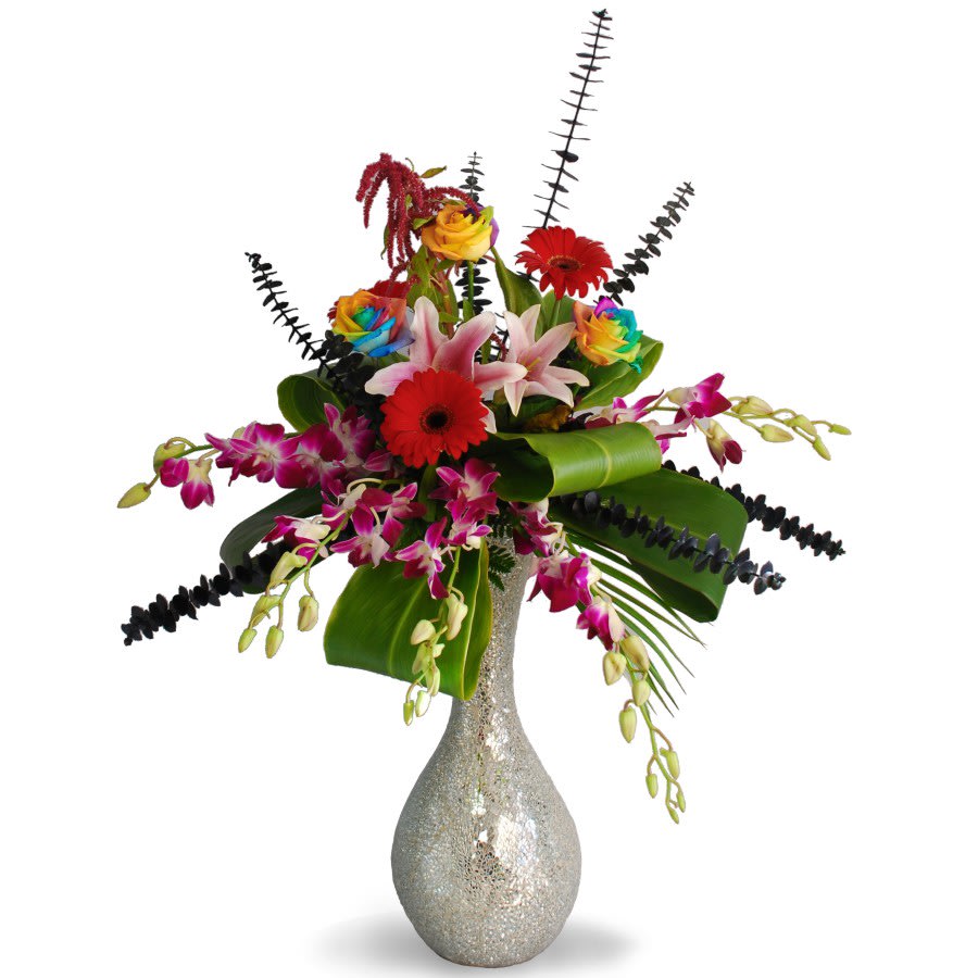 Enchanted Enchanted - Add variety to a normal arrangement with "Enchanted", featuring our selection of rainbow roses, lilies, gerbera daisies, and more! The arrangement is supported by a sparkling mirror vase.