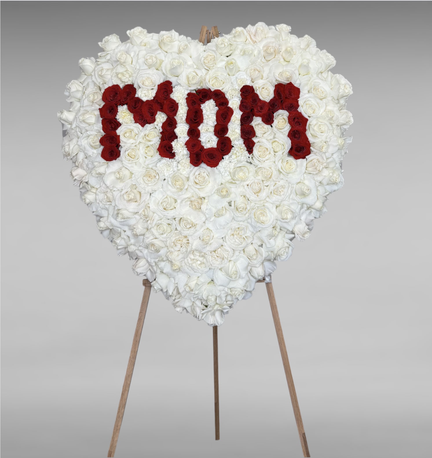 Prayers, Peace, Blessings - Their pure heart and peaceful spirit will live on in a gesture symbolizing the heart of eternal life. Our standing heart of soothing white roses and fresh red roses, expertly crafted by our florists for a lush, full presentation, is a grand expression of your condolences, offering hope and serenity during a difficult time. All-white standing heart arrangement with white roses, red roses, and carnations.