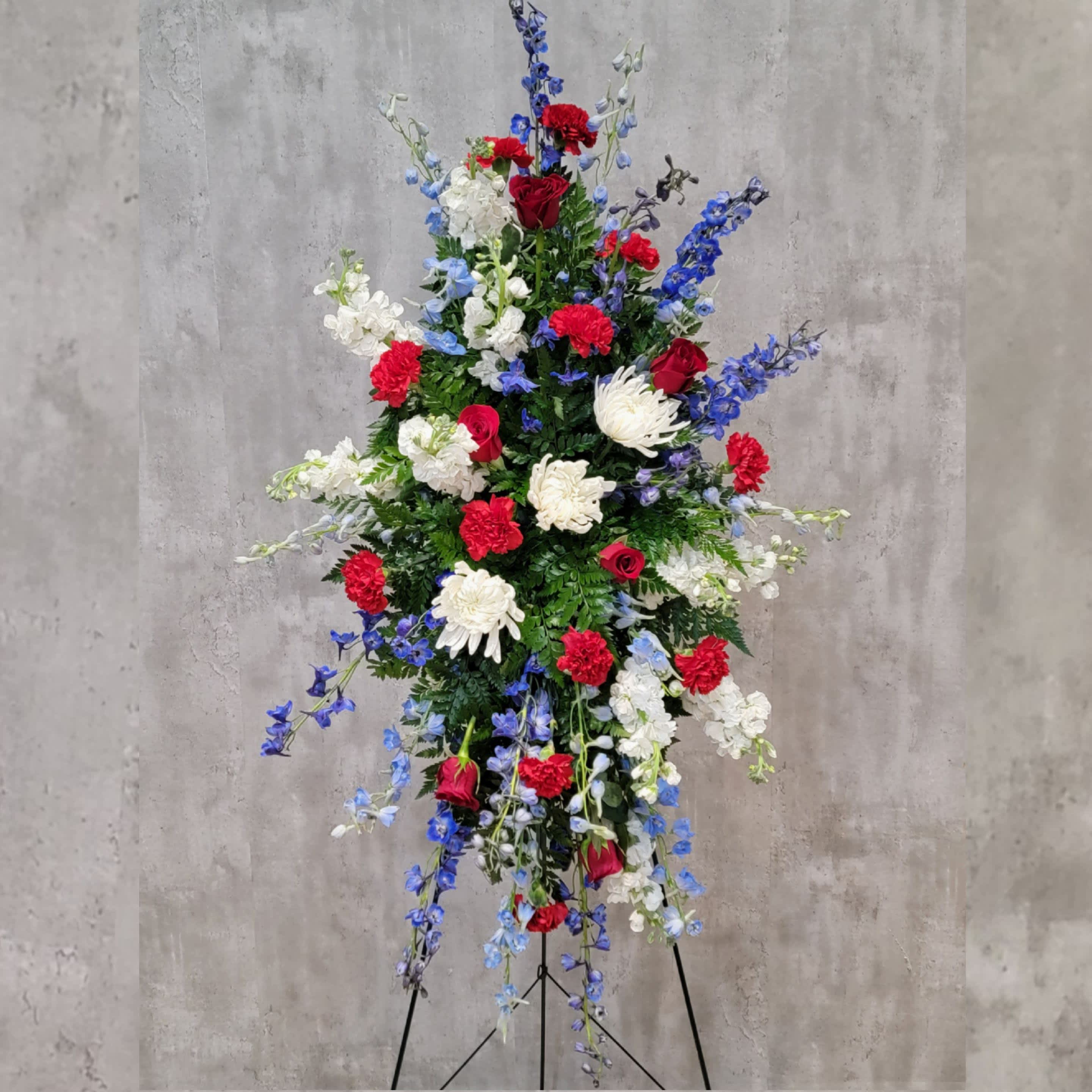 Patriotic Serenity Easel - This patriotic red, white, and blue easel is a great sentiment of sympathy to the family of any service member. Gladiolus, roses, lilies, carnations and delphinium create a beautiful, respectful  spray.   Your reliable Albuquerque florist, locally owned and operated is ready to delivery your fresh flowers within Albuquerque. Flowers by Zach-Low has been serving the Albuquerque area since 1993 and offers same day flower delivery in Albuquerque. Delivering fresh flowers in Albuquerque is a passion that drives Flowers by Zach-Low to be the best Albuquerque florist in town.