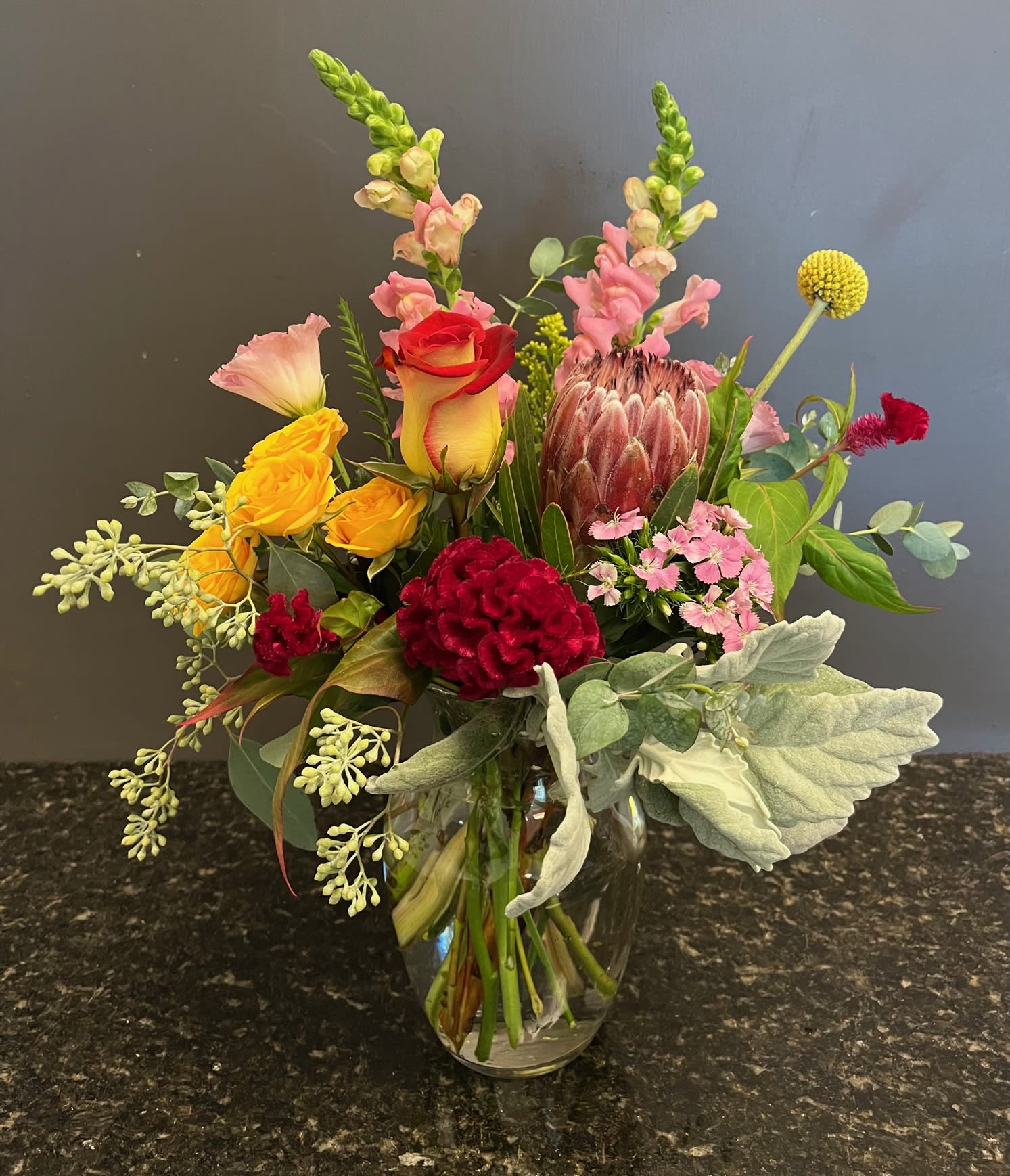 Sonata #5 - A fancy mix of flowers with a Protea. Mix will include snapdragons, spray roses, dianthus, cockscomb, seeded eucalapytus and fancy greenery