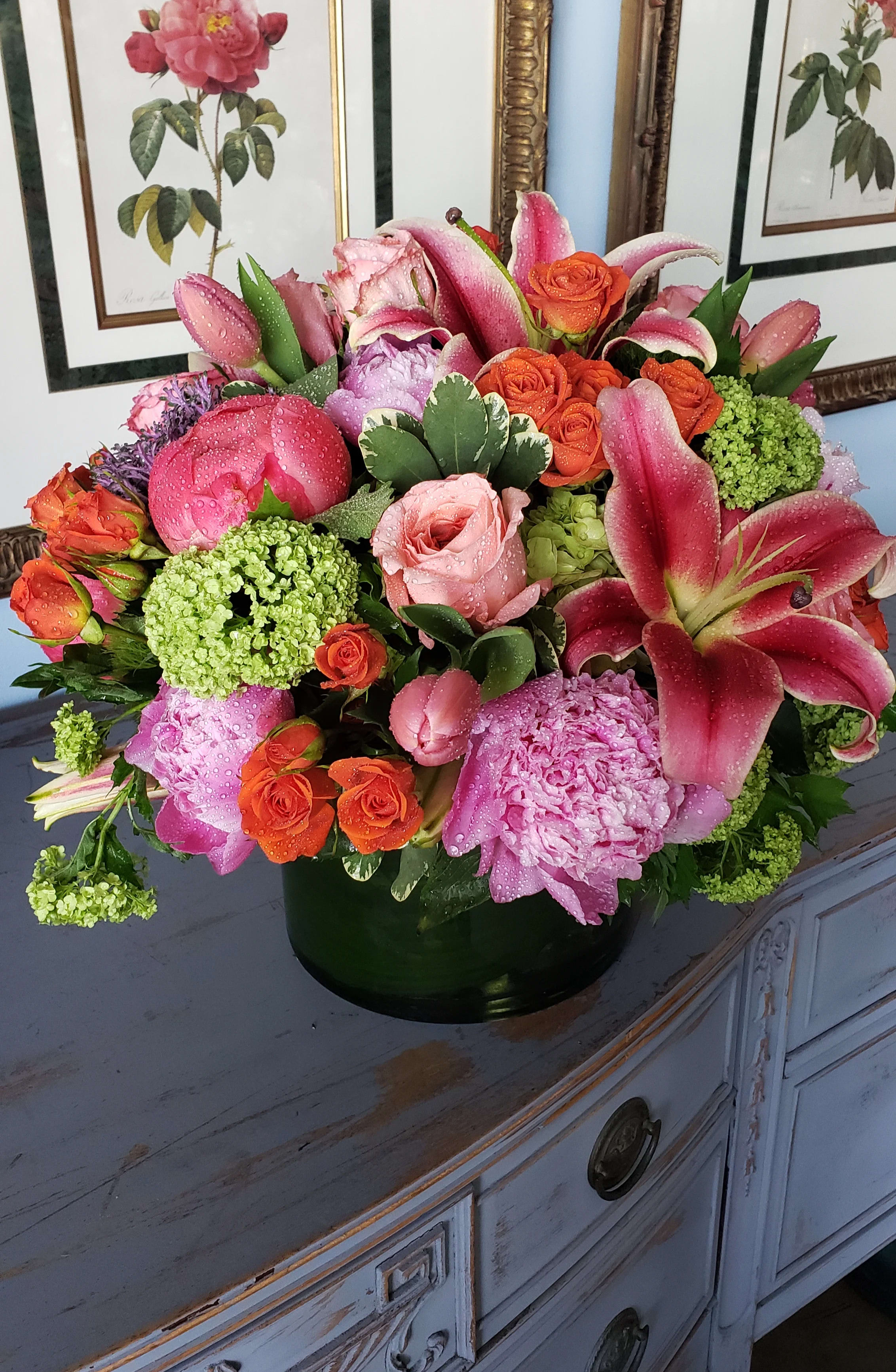 Vivid Euphoria  - Elegant cylinder filled with summer vivid flowers such as coral peonies, oriental lilies, pink garden roses, verbarium blooms, green hydrangeas, tulips, and spray roses.  **Pot color may vary**  At Belden's Florist we stand behind the quality of our products. We guarantee that our flowers will remain fresh and beautiful for 3-5 days after delivery. As cut flowers, they may naturally start to wilt beyond this timeframe. However, we ensure that you receive the freshest blooms possible, carefully selected and expertly arranged to bring joy and elegance to your space. To help your flowers stay fresher longer, we recommend adding fresh water to the vase regularly. Just like you, flowers need hydration to thrive, and refreshing the water allows them to drink up and continue to dazzle you with their beauty.