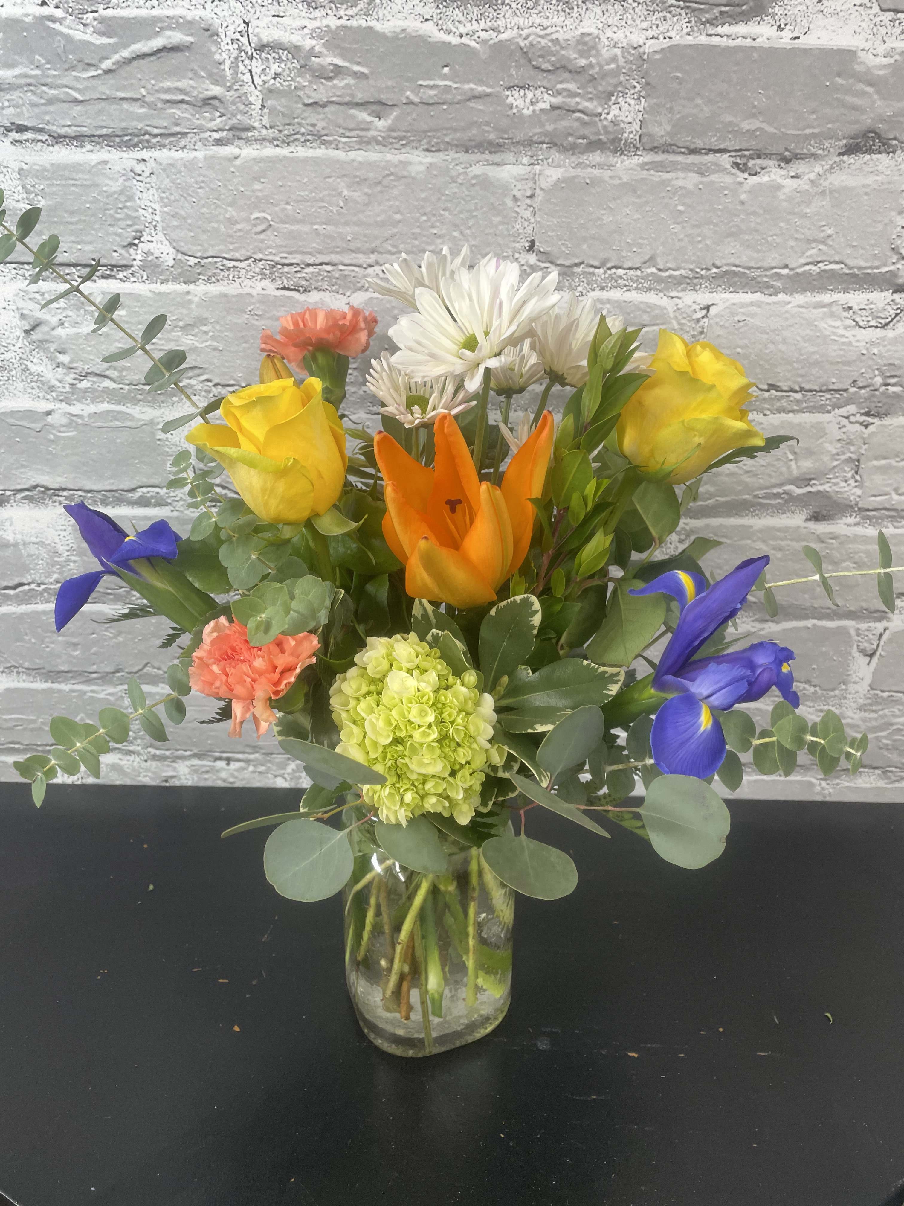 Harmony - Fun combination of orange lilies, yellow roses, iris, combine with daisies,  hydrangea, and eucalyptus to create this bouquet.