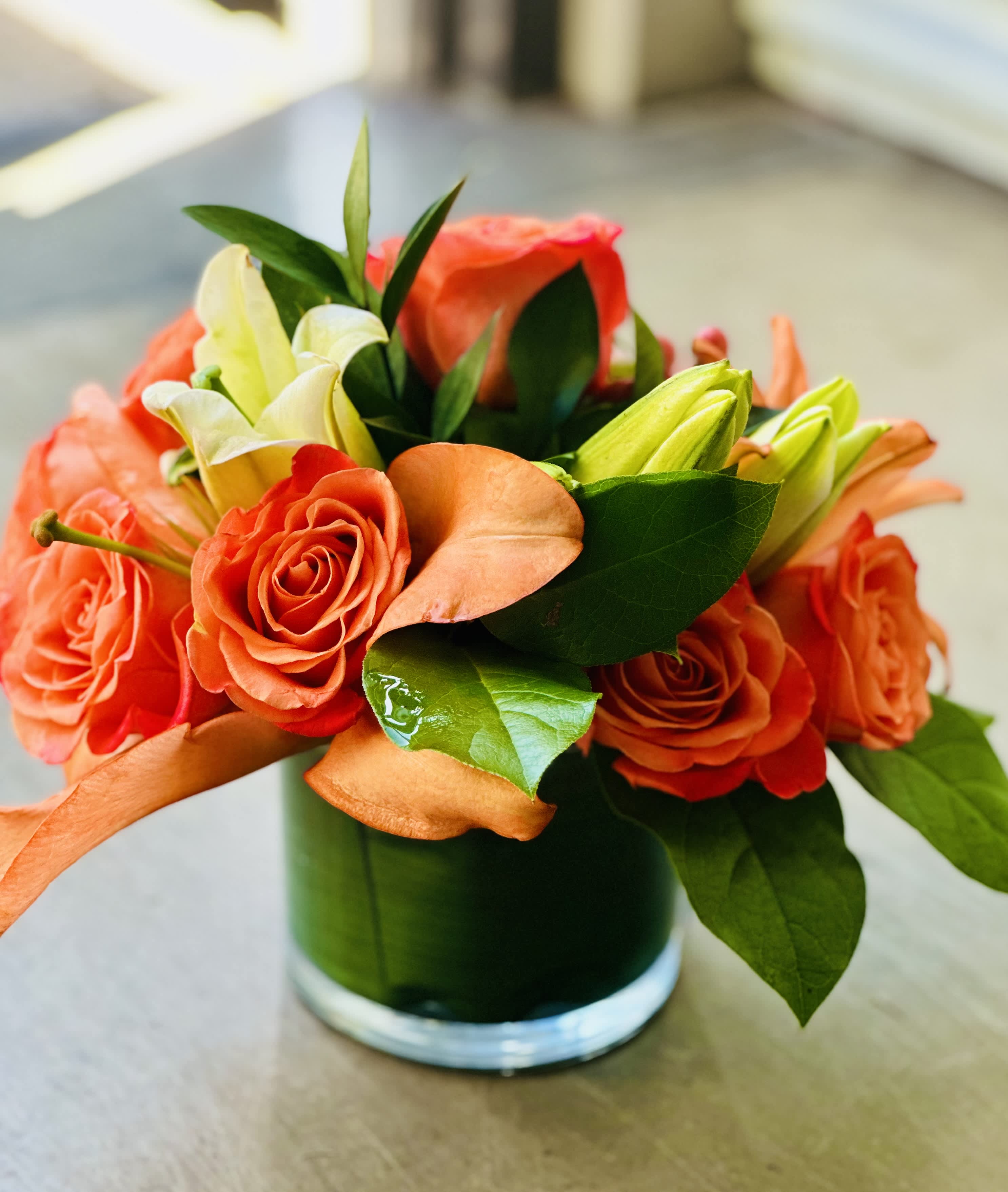 Tangerine Dream Tangerine Dream - Orange Roses Lemon leaf & Israeli ruscus Hypericum berries Lillies White/Orange/Yellow (color may vary)