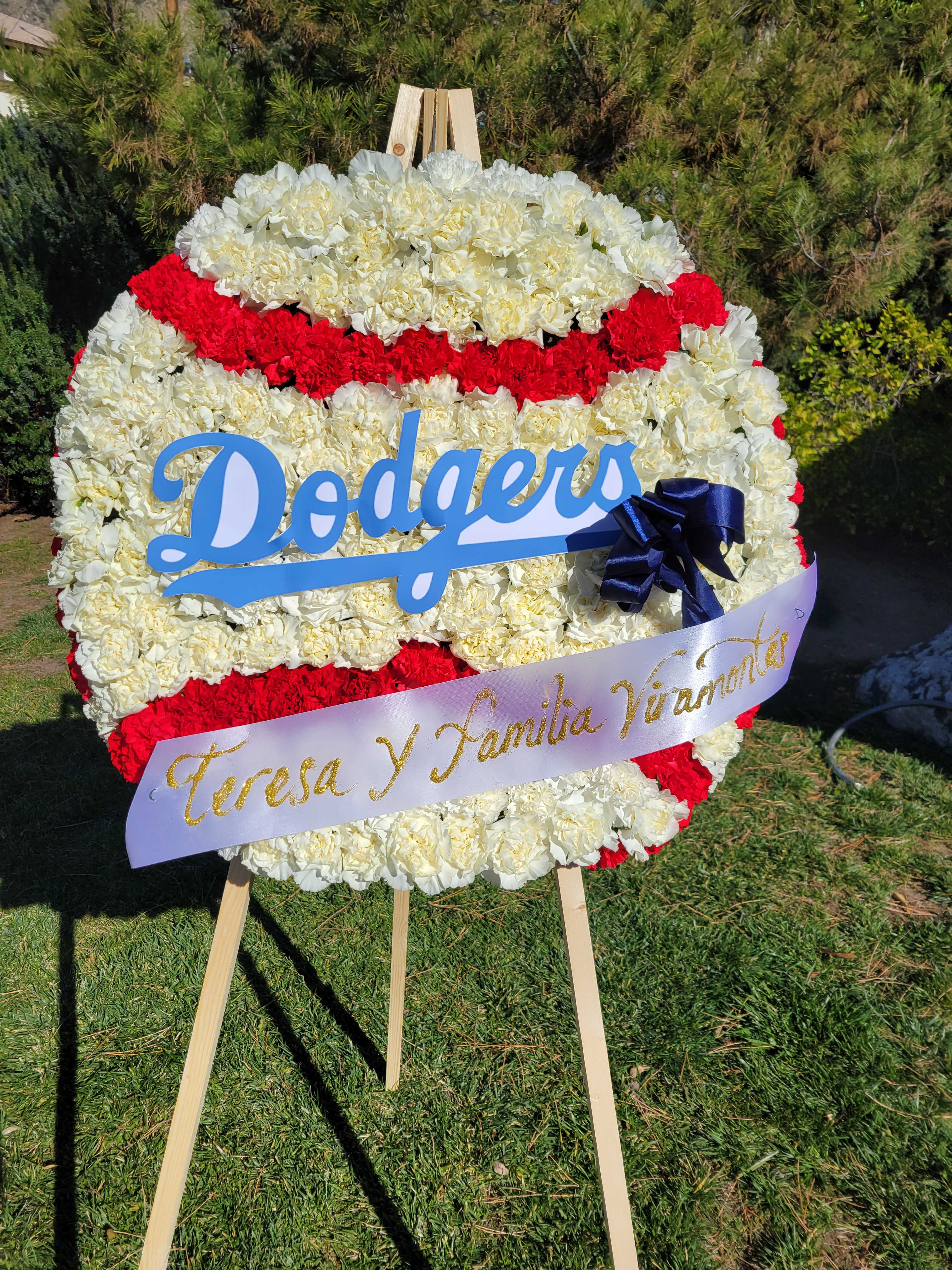 Dodger Tribute - This funeral standing spray is a custom design resembling a baseball. The dodgers tribute spray has been a popular choice for loved ones who wanted something uplifting to commemorate the memory of their loved one.   This item comes delivered straight to your service and is fully equipped with a funeral stand.