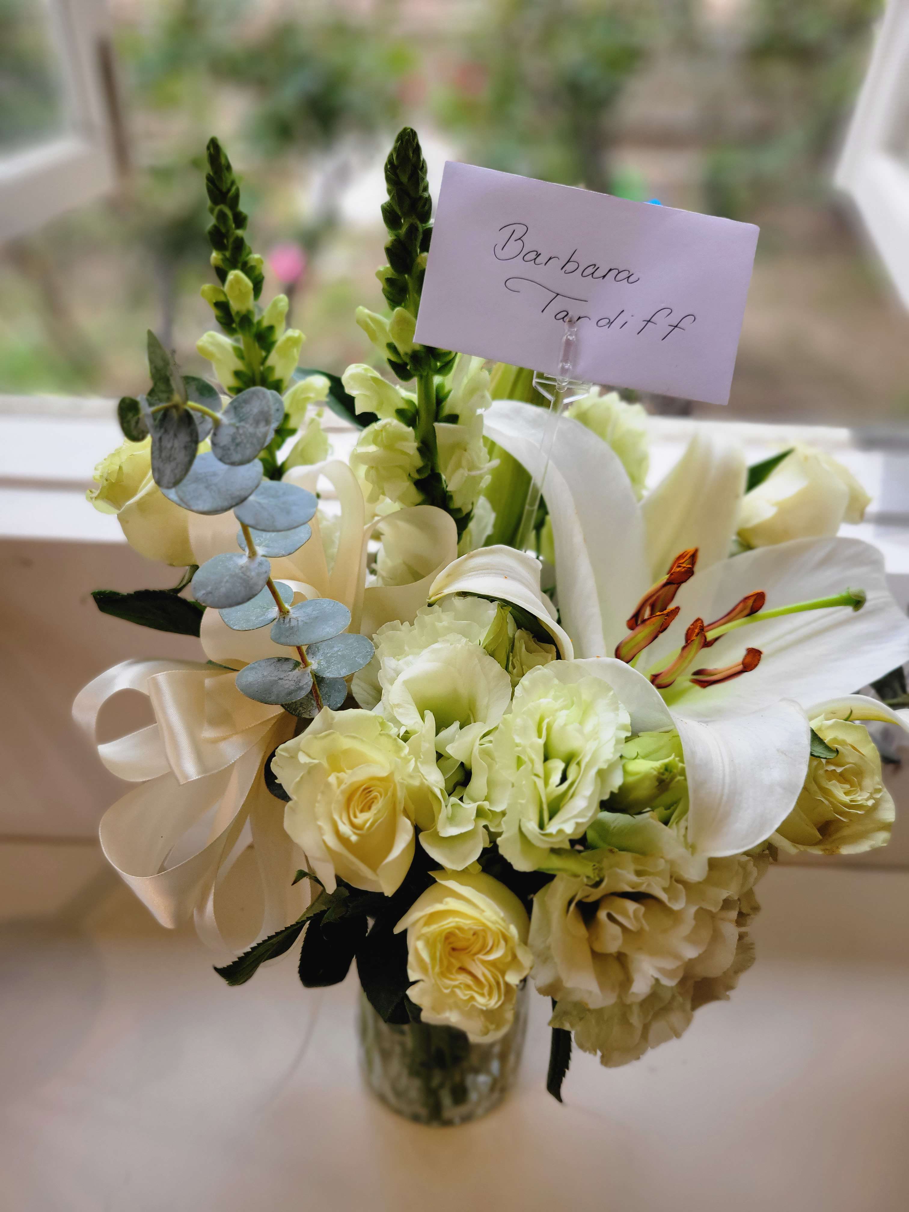 Treasured Time - All white Sympathy arrangement for the home featuring all white snap, lily, roses, and lisianthus.