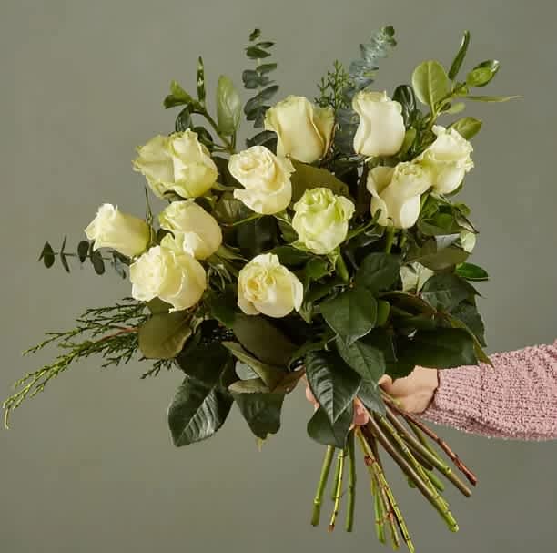 Eternal Embrace Bouquet - Indulge in the timeless beauty of our exquisite hand-tied bouquet of white roses, elegantly intertwined with fragrant eucalyptus and cedar, offering a fresh and vibrant twist perfect for Mother's Day and the rejuvenating spirit of spring. Radiating with the delicate charm of the season, this arrangement exudes elegance and sophistication, making it an unforgettable gift to celebrate the cherished mothers in your life or to brighten any springtime occasion.  Please Note: While we always strive to follow the color palette, we may replace stems to deliver the freshest bouquet possible, ensuring that your arrangement is as vibrant and delightful as can be, just like the blooming season of spring.
