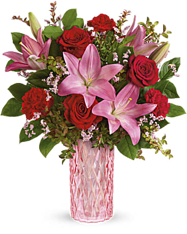  Romanced By Roses Bouquet - An elegant Valentine's Day delight, this romantic, diamond-cut glass vase is the prettiest shade of pink--the perfect complement for ravishing red roses and pink lilies. This bouquet features red roses, pink asiatic lilies, red carnations, pink limonium, red huckleberry and lemon leaf. 