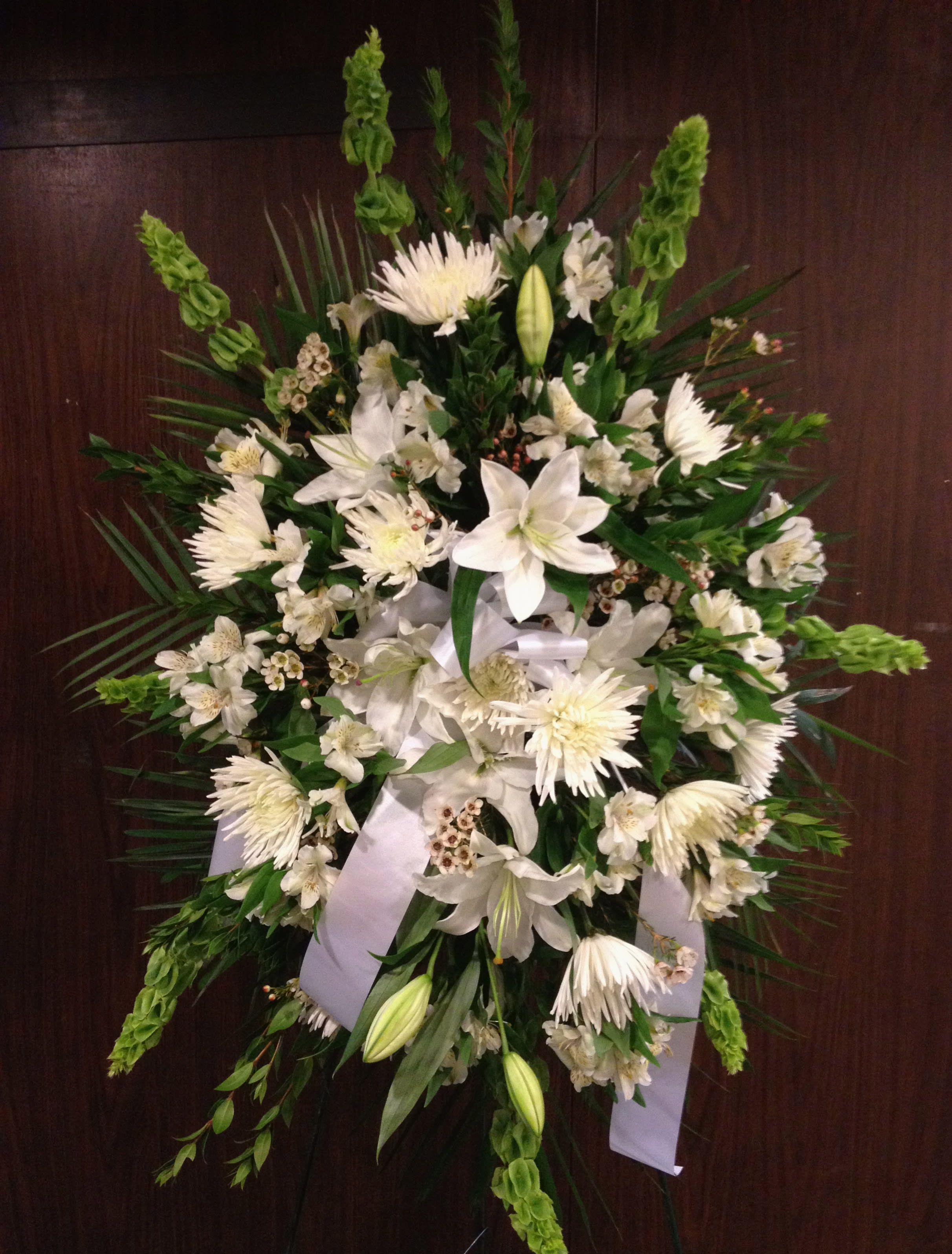 White and Green standing Spray  - To send sympathy flowers is a testament of your love and devotion. This serene standing spray with white and green lovely flowers such as lilies, chrysanthemums and alstroemeria.  