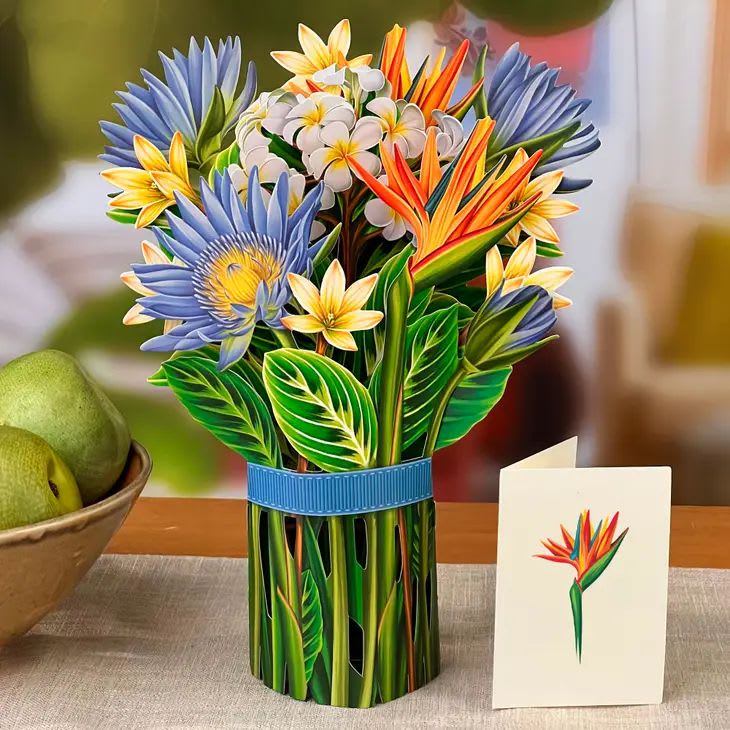Tropical Bloom Pop-up Greeting Card - A journey of color and design, this whimsical Tropical Bloom bouquet evokes the promise of the future. Showcasing Birds of Paradise representing optimism, Lotus blossoms symbolizing rebirth and Plumeria for hope, this bouquet will uplift.  •  Made in China •  Weight: 4 oz (113.4 g)