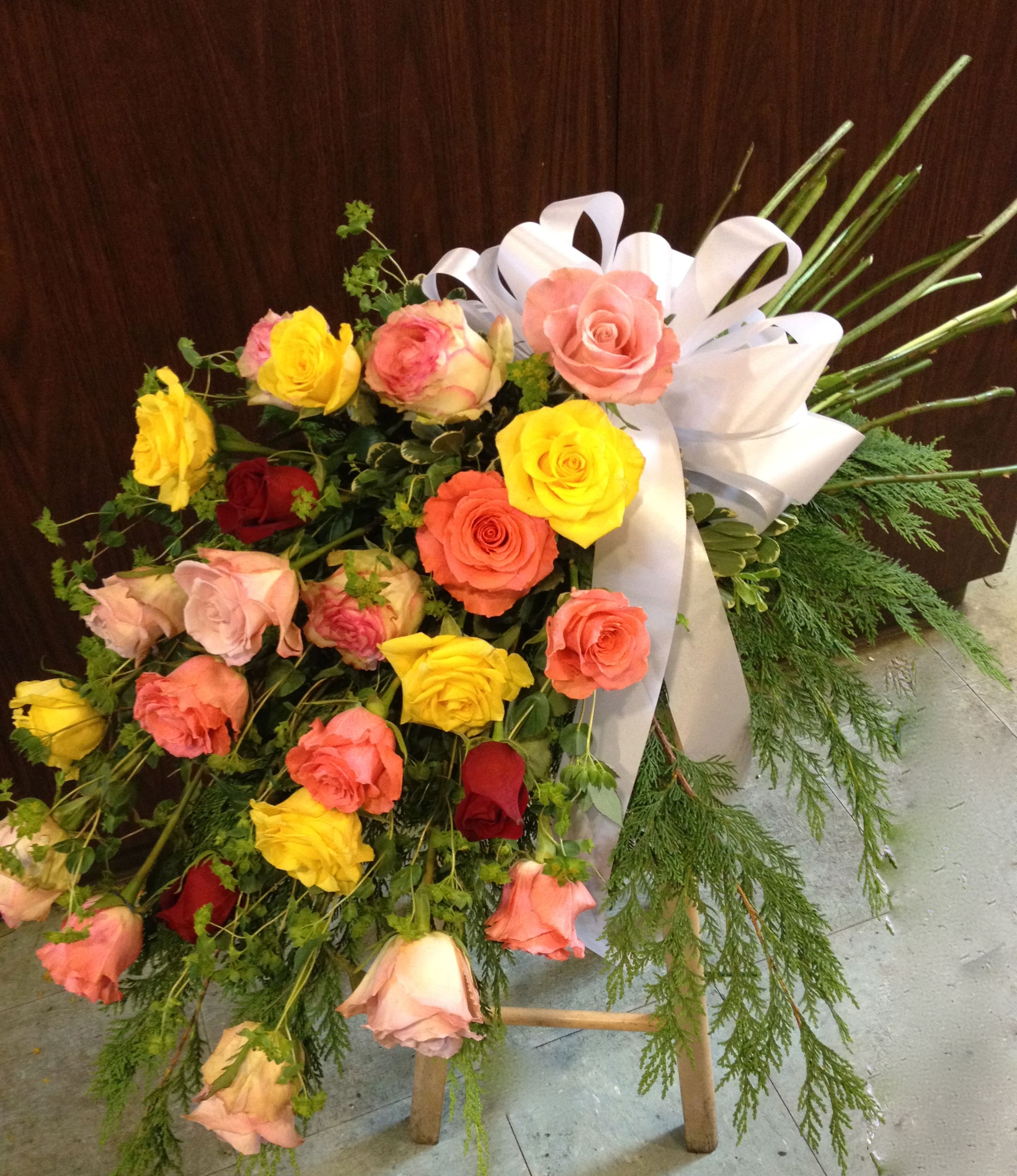Mixed Color Rose Casket Bouquet  -  Celebrate a life well lived and loved with this beautiful casket bouquet. Roses in a variety of colors are arranged to look like a natural bouquet laying across the casket. 