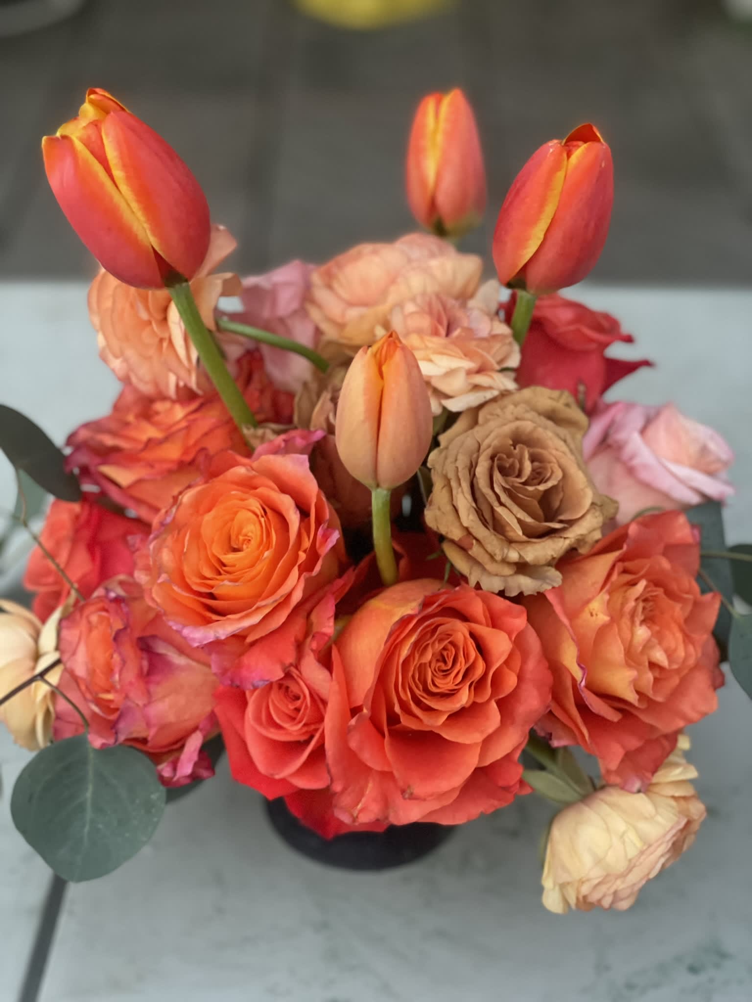 Tuscan Sunset - This unique and vibrant compact arrangement is bright and bold. Its unique colors capture the terra cottas, pinks, and oranges of a Tuscan sunset. The ranunculus lends its elegant charm to this bold combination,while the unique mocha roses pull the lighter and darker tones together beautifully. A simple yet joyful combination that is sure to capture attention and adoration.