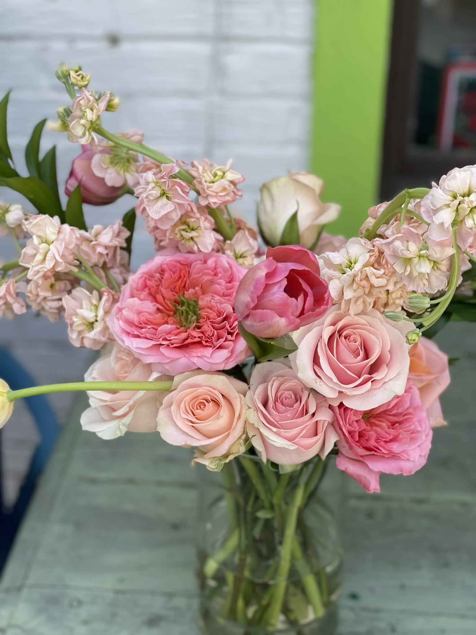 Pink Paradise - This arrangement is as Fun as it is Gorgeous. The simplicity of the color palate highlights the elegant shapes and textures of the blooms, making each one stand out. The Garden Rose with the green eye steals the show, while the peach stock and tulips give this beauty a sense of movement and grandeur. This one is sure to delight even the most discerning flower lover! 