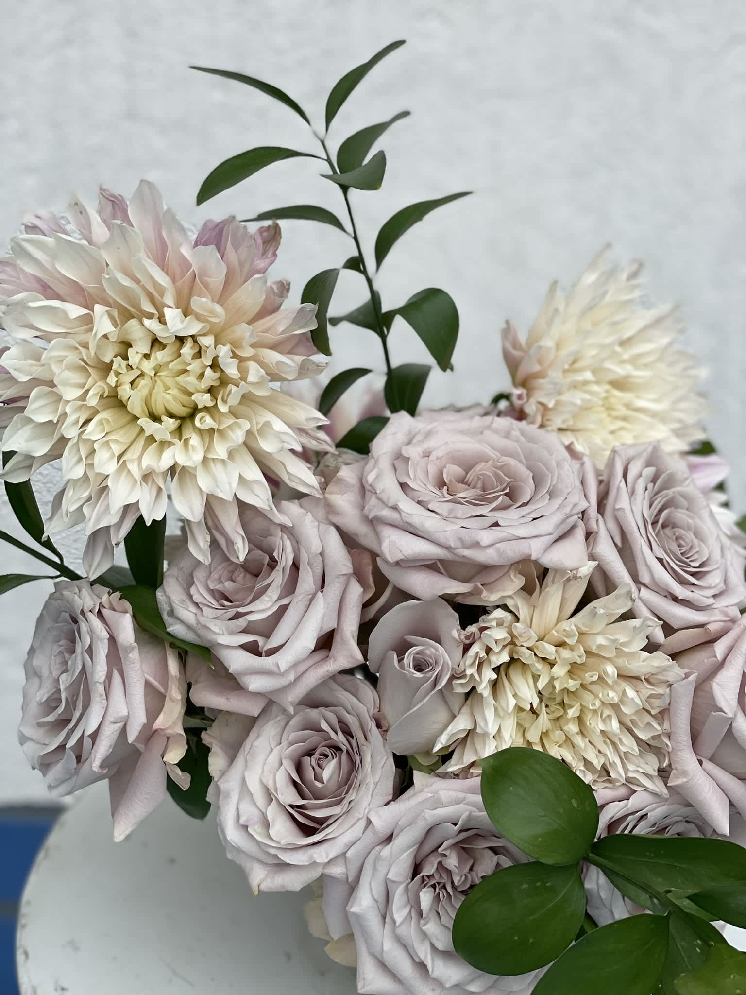 Quicksand  - This rare and unique arrangement is striking in its simplicity, the muted color of the Quicksand Roses highlights their elegant shape and petal folds. The tone of the roses sets itself somewhere between lavender and white, while the Cafe Au Lait Dahlias bring it all together with their large, wild blooms.