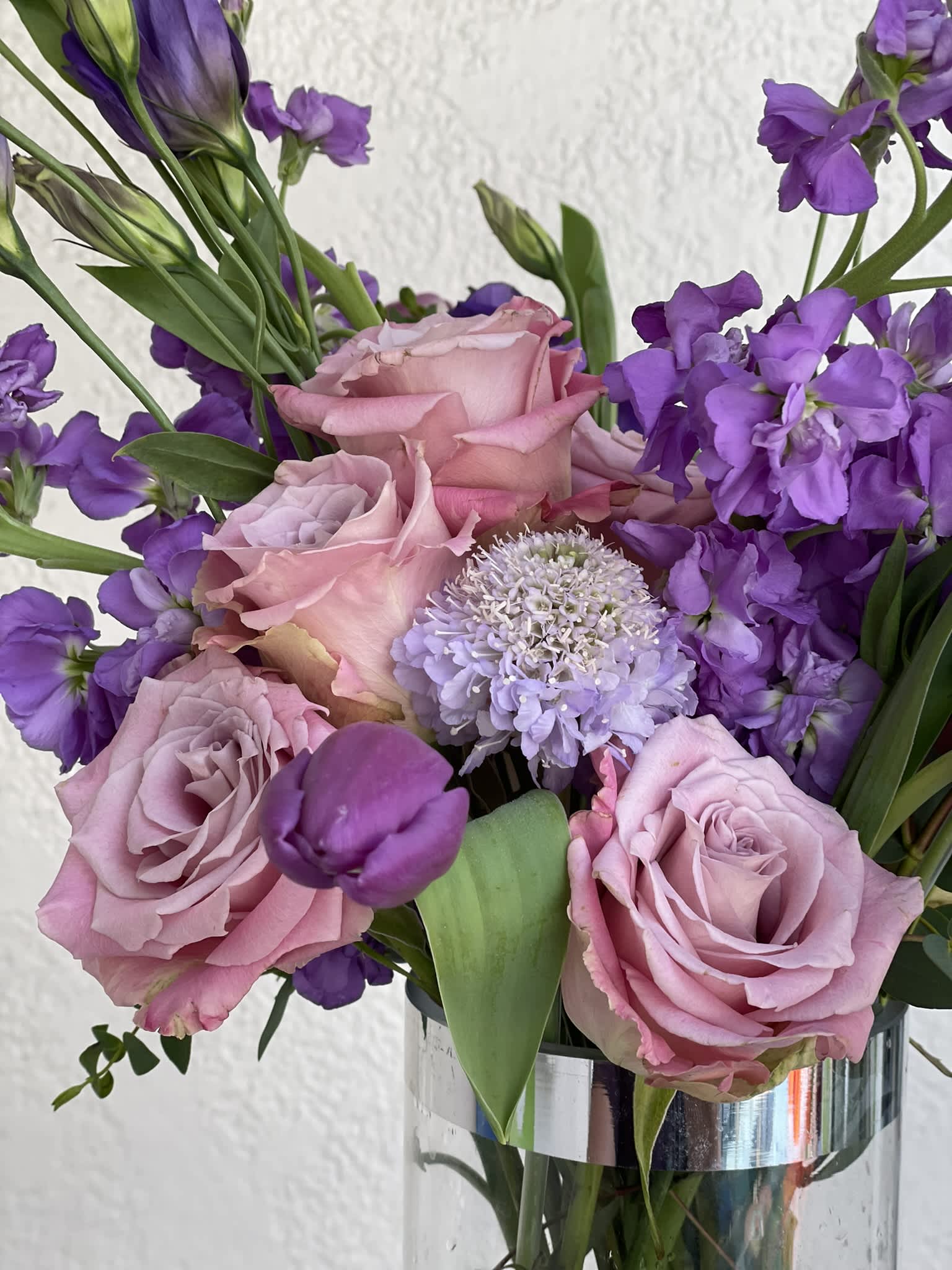 Lavender Dream - This arrangement boasts a striking spectrum of purple, from lavender to deep violet. Its structure give it an elegant and stately look, while the colors lend a fun and calming effect. The deep violet of the tulips and lisianthus towering above the lavender roses and scabiosa give this combination incredible contrast, while the electric lavender stock pulls the entire look together. This piece is a crowd pleaser, and is bound to make any room, event, or person happy!