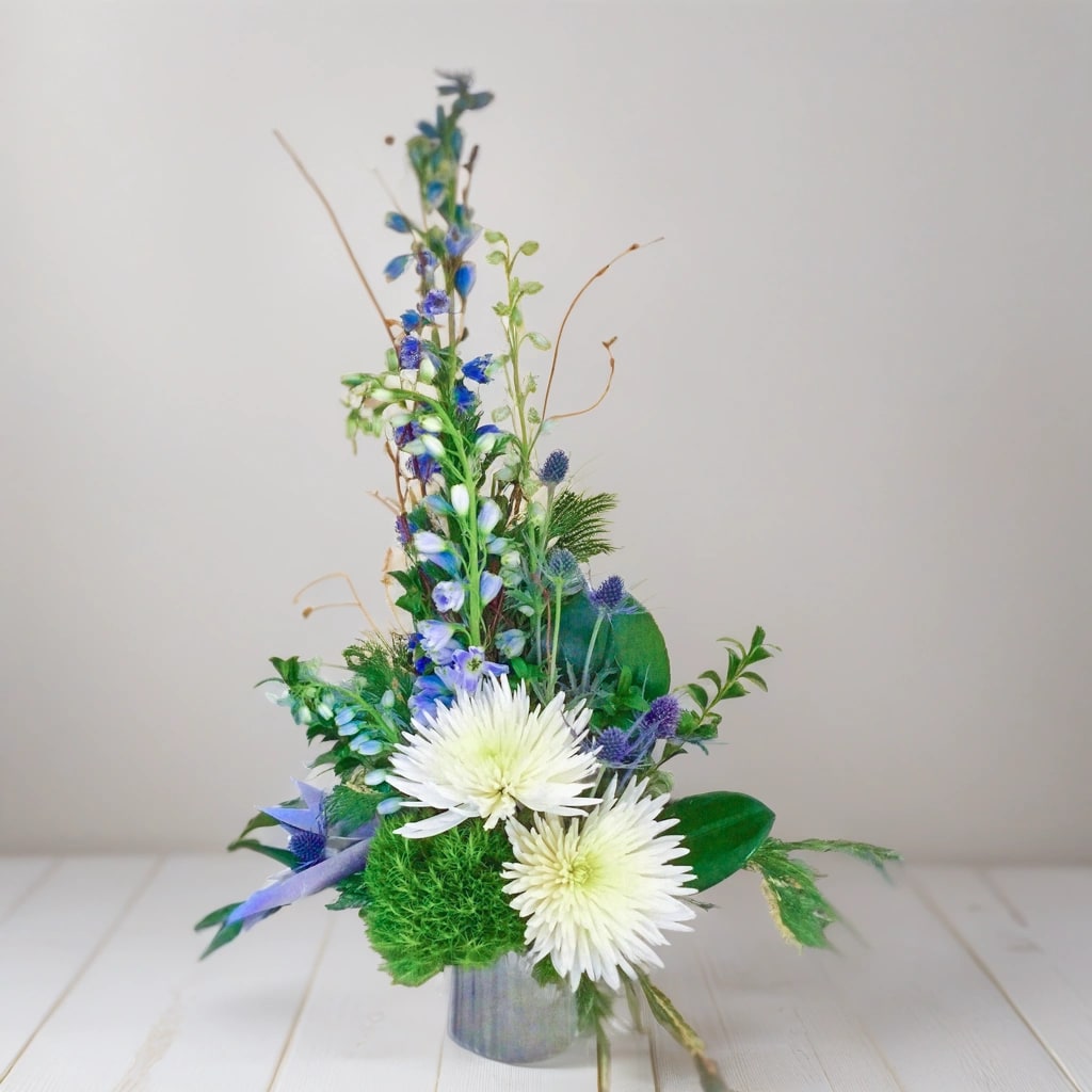 Best in Show - Looking to brighten someone's day or express your gratitude? Look no further than our sweet little floral arrangement, &quot;Best in Show&quot;!  This captivating bouquet features a delightful combination of vibrant blue delphinium and elegant white spider mums. The contrasting colors create a visually striking display that is sure to leave a lasting impression.  Whether you want to say thank you, celebrate a job well done, or simply uplift someone's spirits, &quot;Best in Show&quot; is the perfect choice. Its beauty and charm will bring joy and positivity to any occasion.  Surprise a loved one, brighten up your home, or bring a smile to a friend's face with this enchanting floral arrangement. Let the delicate blooms work their magic and spread happiness all around.  Order your own &quot;Best in Show&quot; bouquet today and make someone's day unforgettable! 