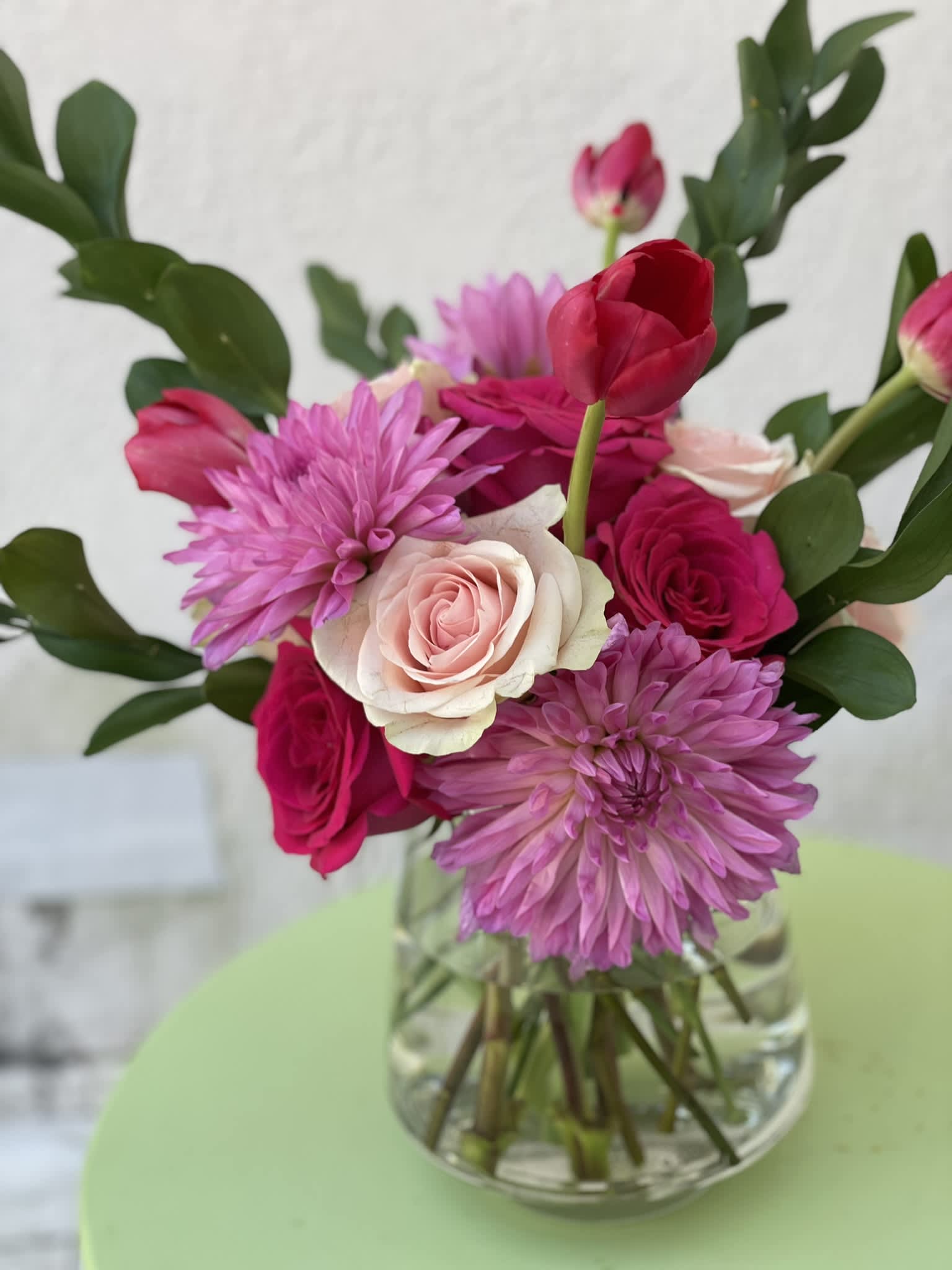 Pink Romance - This exquisite combination of deep pinks to blush creates a display that would make anyone swoon. The bright pink Dahlias and deep red tulips add even more unique shape and texture to this sweet arrangement.