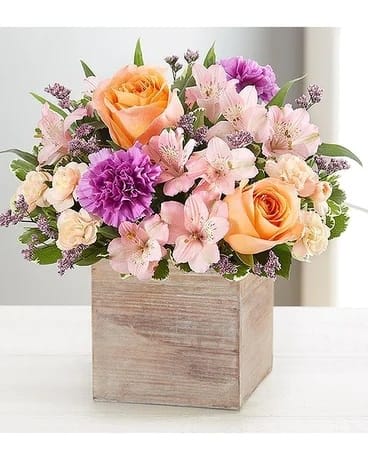 Chic Garden - Chic meets sweet. Our new bouquet flaunts fresh spring style, gathered with a mix of coral, pink, peach and lavender blooms. Designed in our rustic, grey-washed wooden cube for a cool contrast of color, it’s like giving them their own gorgeous garden right at home. 