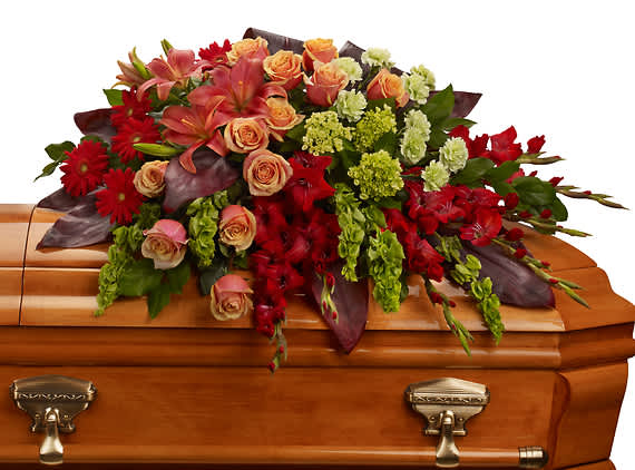 A FOND FAREWELL CASKET SPRAY - Bring majesty to the service with this gorgeous casket spray of orange roses and lilies and other brilliantly colored floral favorites. A touching tribute for someone special.  
