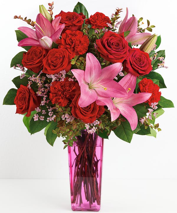 PRETTY &amp; PINK  - Gorgeous long-stem red roses and carnations are combined with delicate pink lilies all presented in a cute pink vase!