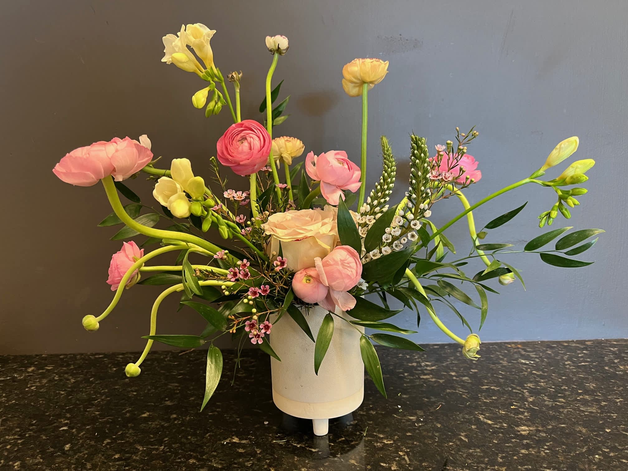 Miss Whimsy  - we have a delightful, fun and airy arrangement with Ranunculus, Roses, Freesia and other floral accents in a cream color ceramic footed container.   