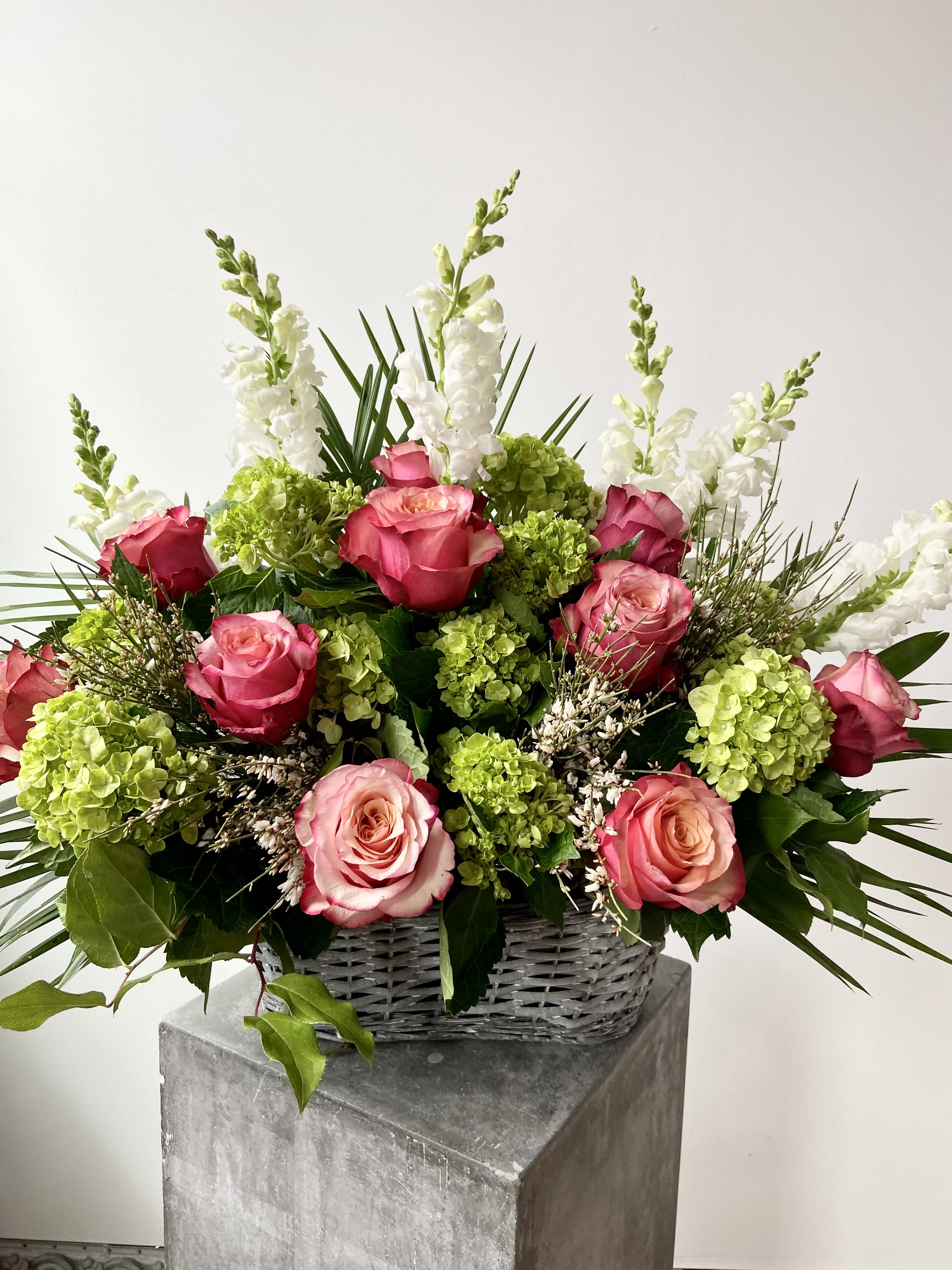 Sympathy Arrangement - Sympathy Arrangement designed in a beautiful rustic basket. Bursting with limelight hydrangea, Coral Pink Roses, White Freesia, and Snapdragons. This piece is a classic way to honor your loved ones. 
