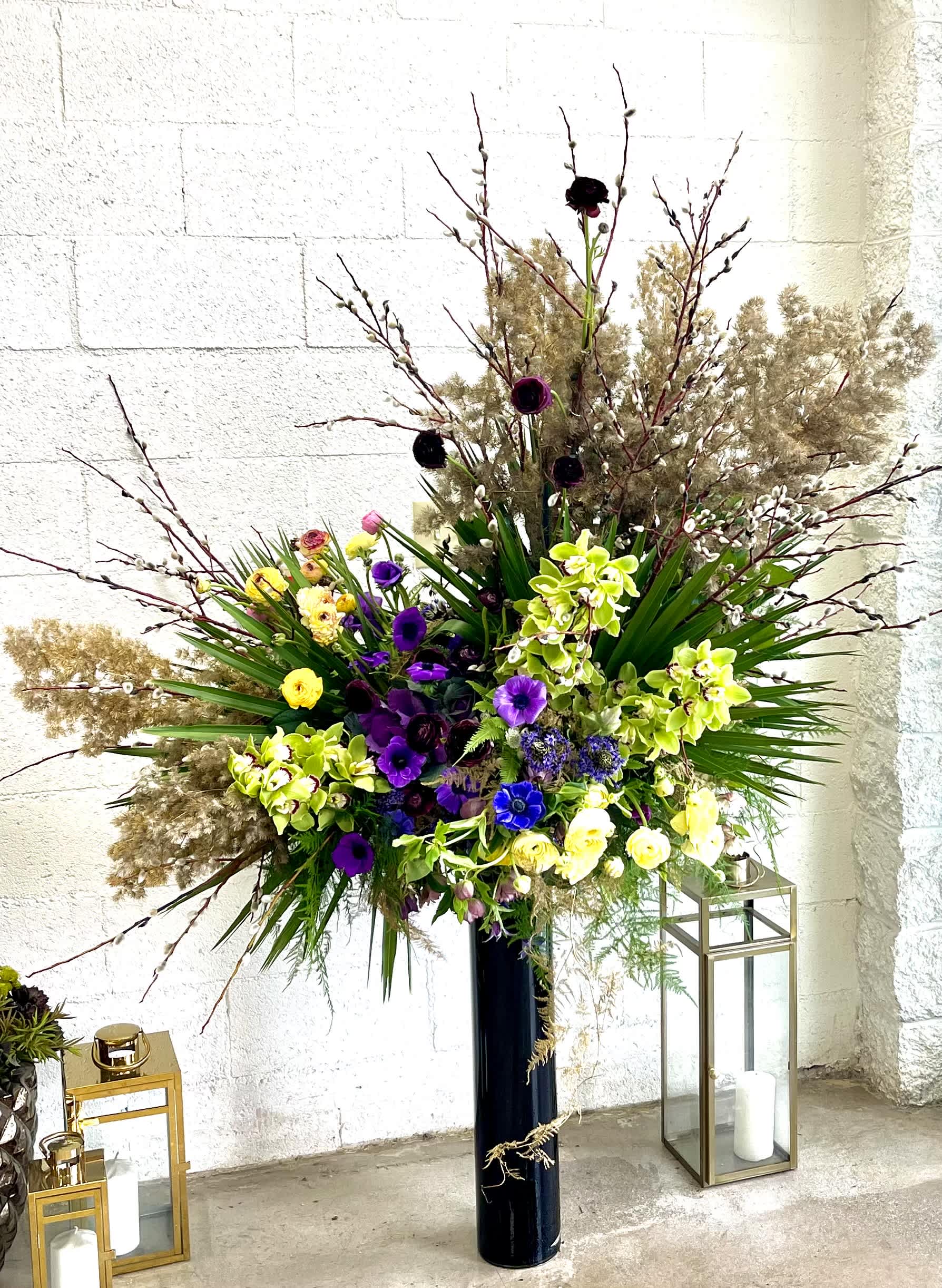 Drama - A large, wild arrangement of assorted flowers and greens that sits atop an impossibly skinny vase. This design is a sure showstopper that defies the laws of gravity!
