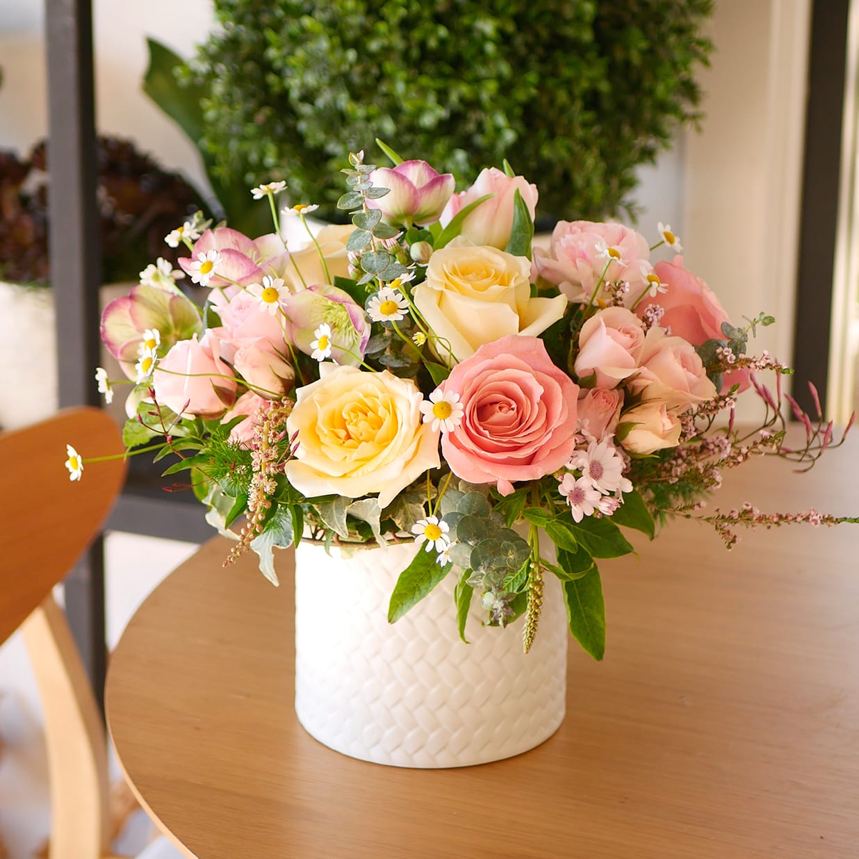 Spring Soirée - This Spring arrangement features a pastel palette of light pinks, whites, and yellows, nestled in a charming white ceramic vessel. Designed with roses, ranunculus, tulips, chamomile, hellebores, ivy and more.